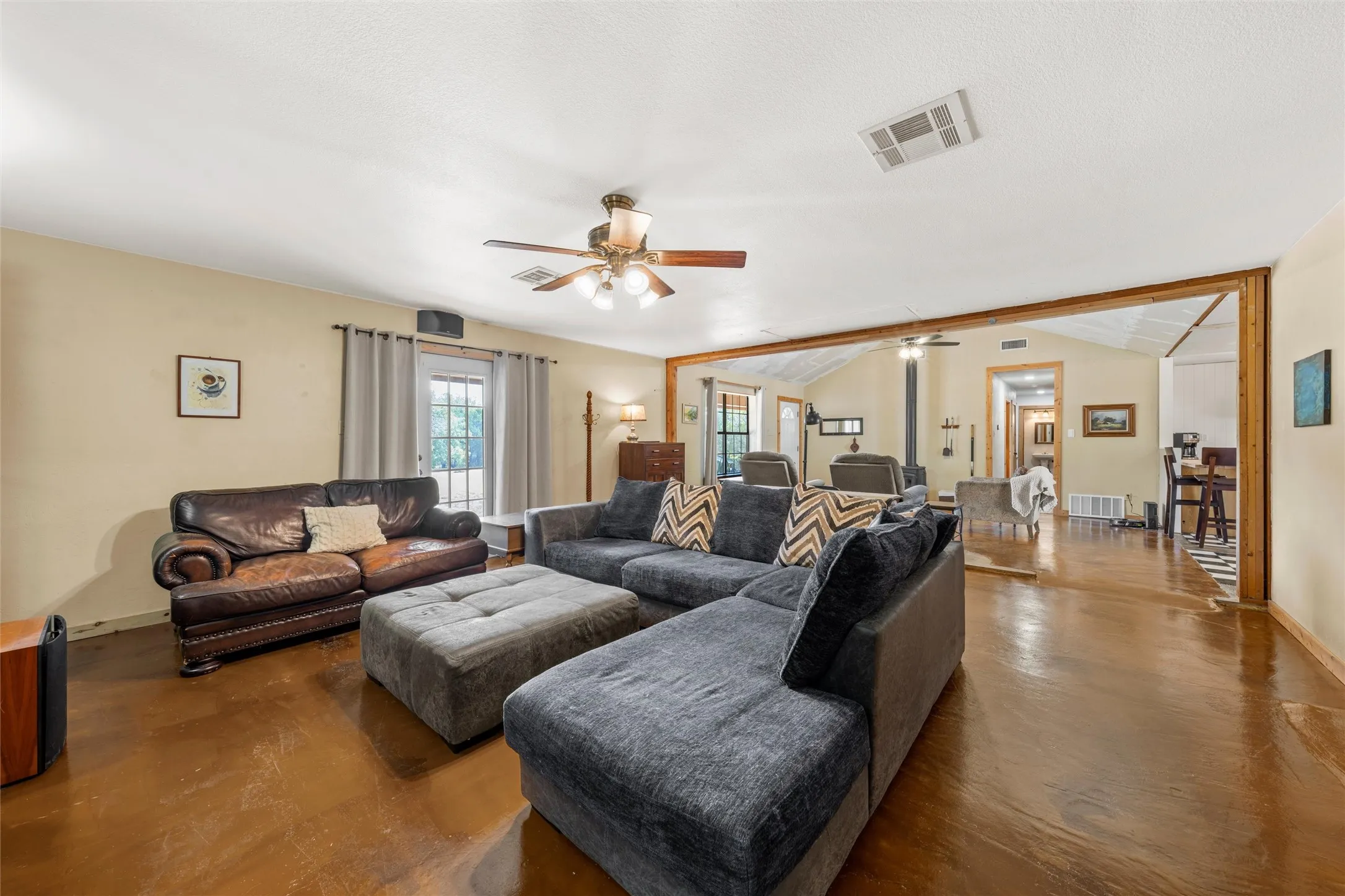 Spacious living area featuring polished concrete flooring, a ceiling fan, and a wood-trimmed doorway
