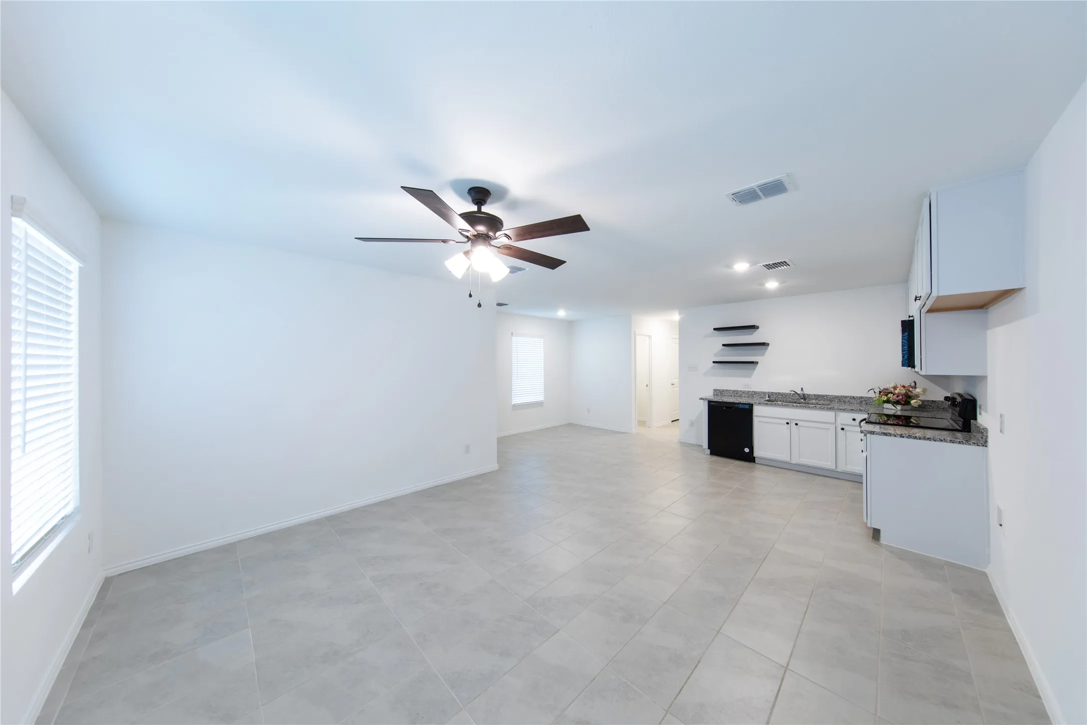 Unfurnished living room featuring sink, ceiling fan, and light tile flooring