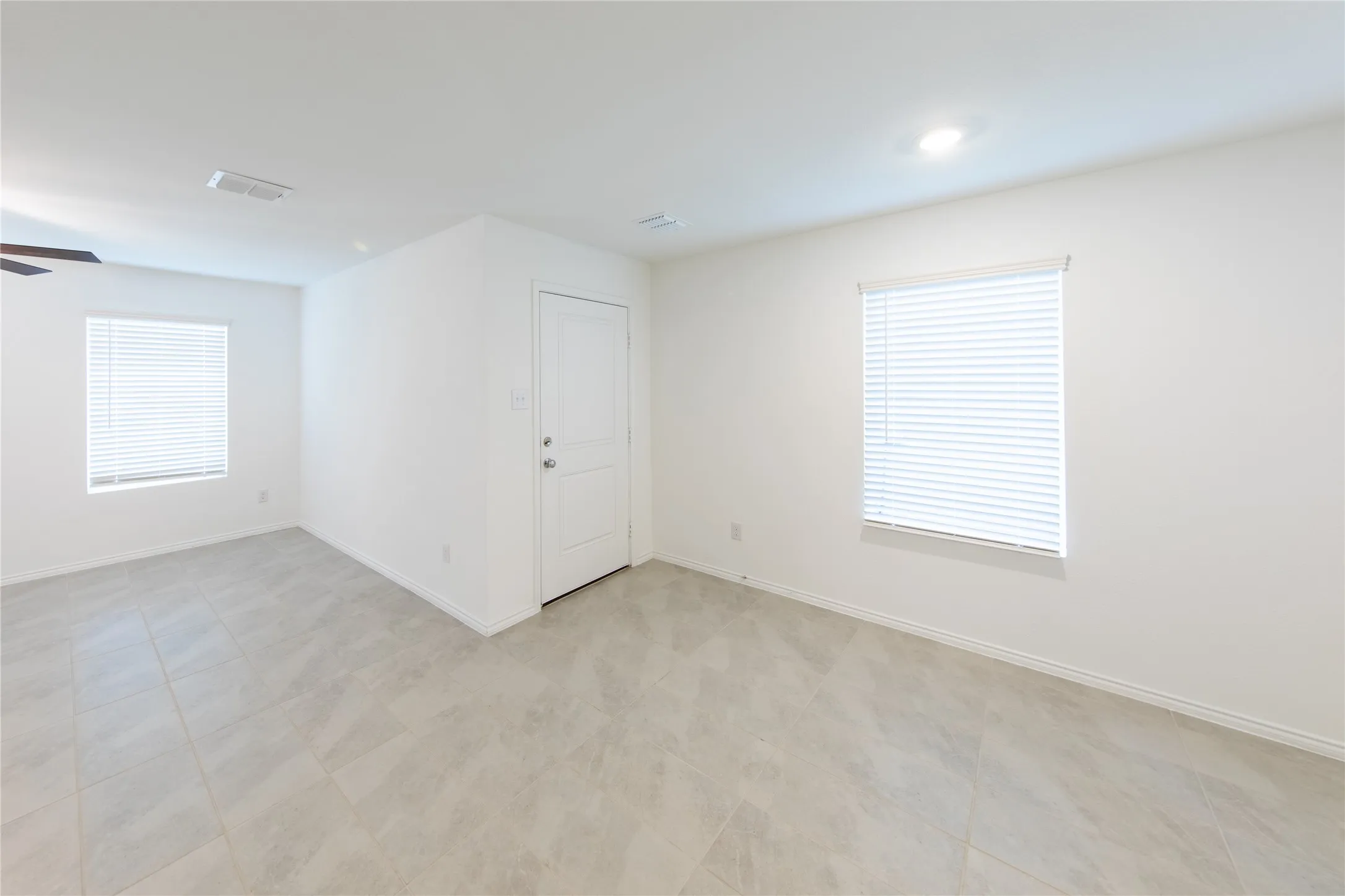 Empty room featuring a healthy amount of sunlight, ceiling fan, and light tile floors