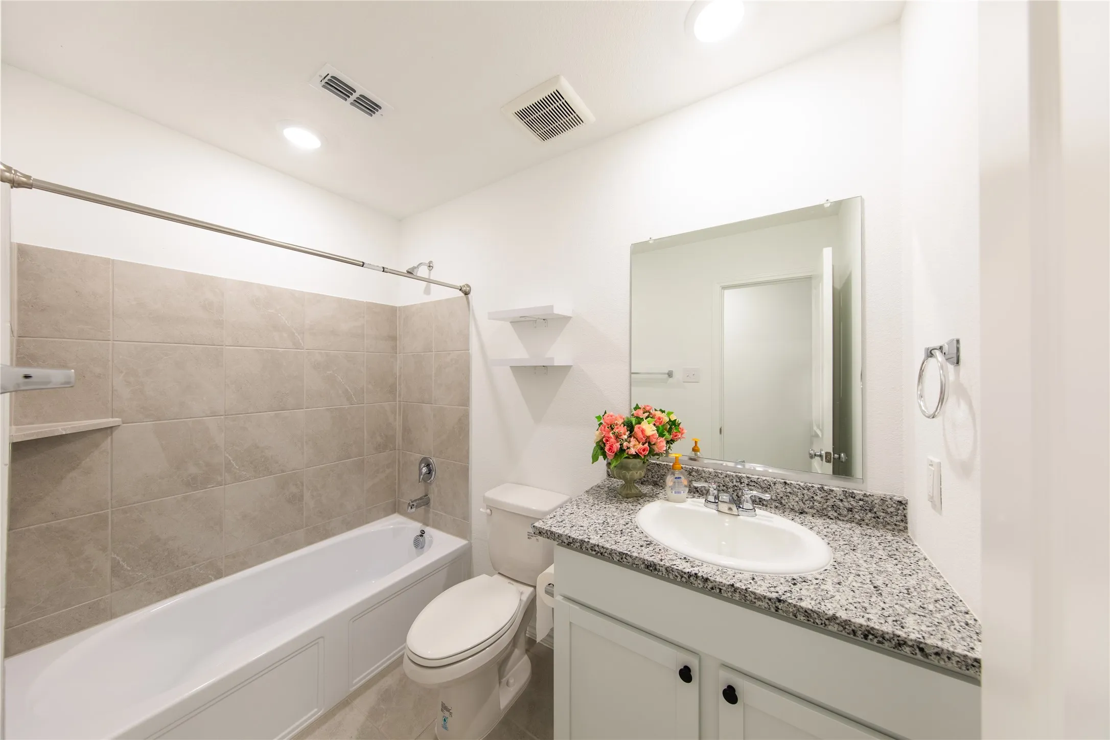 Full bathroom with tiled shower / bath combo, oversized vanity, tile floors, and toilet
