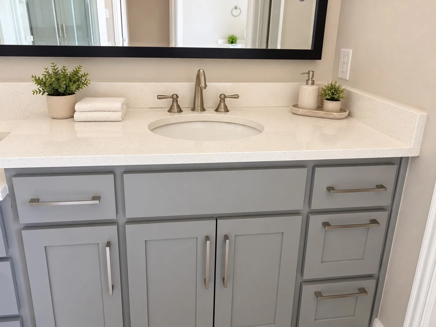 Vanity with light gray cabinetry, brushed nickel hardware, integrated sink, and light-toned solid surface countertop
