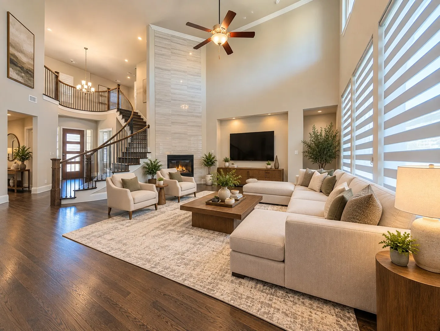 Two-story living area with high ceilings, dark wood-finish flooring, and a fireplace with a light-colored tile surround