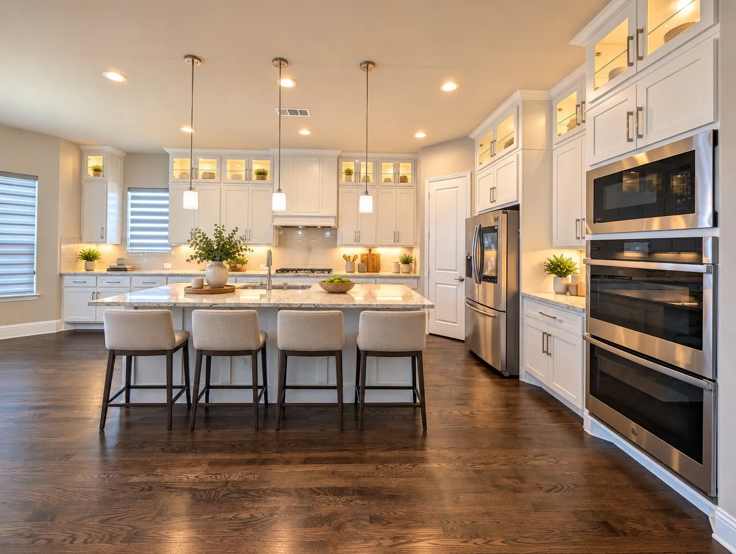 Spacious kitchen with a large central island, white cabinetry, integrated stainless steel appliances, and wood-finish flooring
