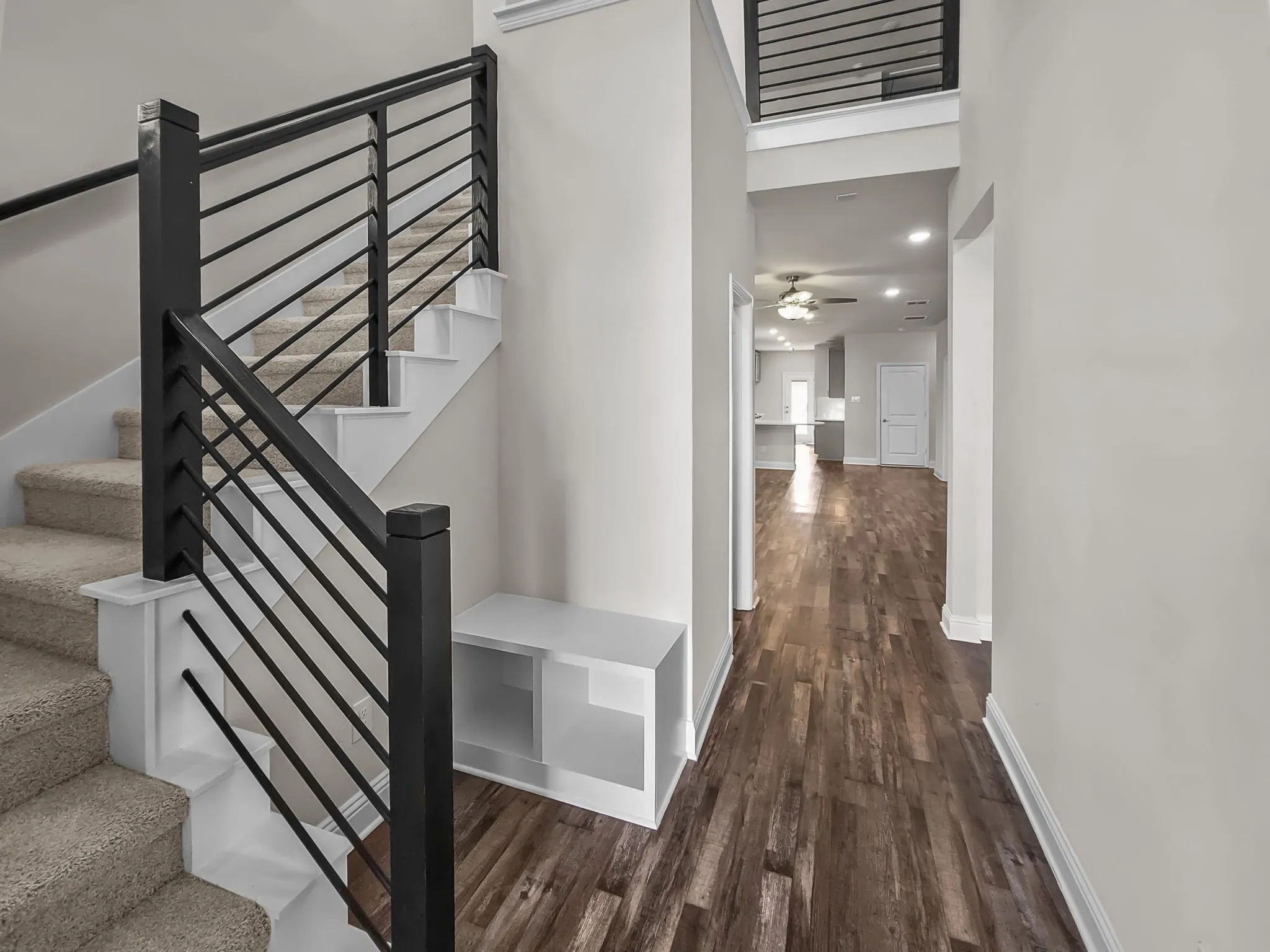 Modern horizontal bar railing, wood-finish flooring, built-in storage bench, and recessed lighting