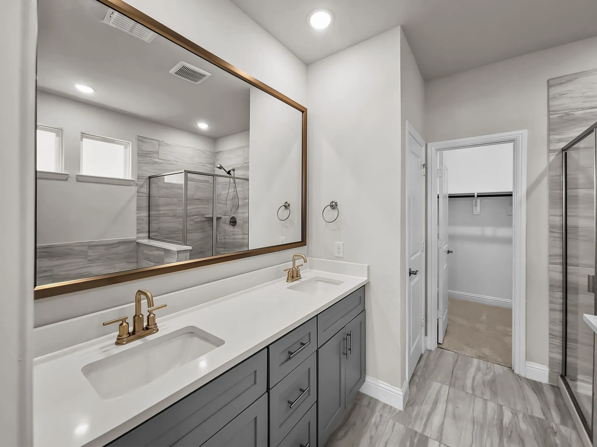 Dual vanity with white countertops, undermount sinks, and brass-finish fixtures