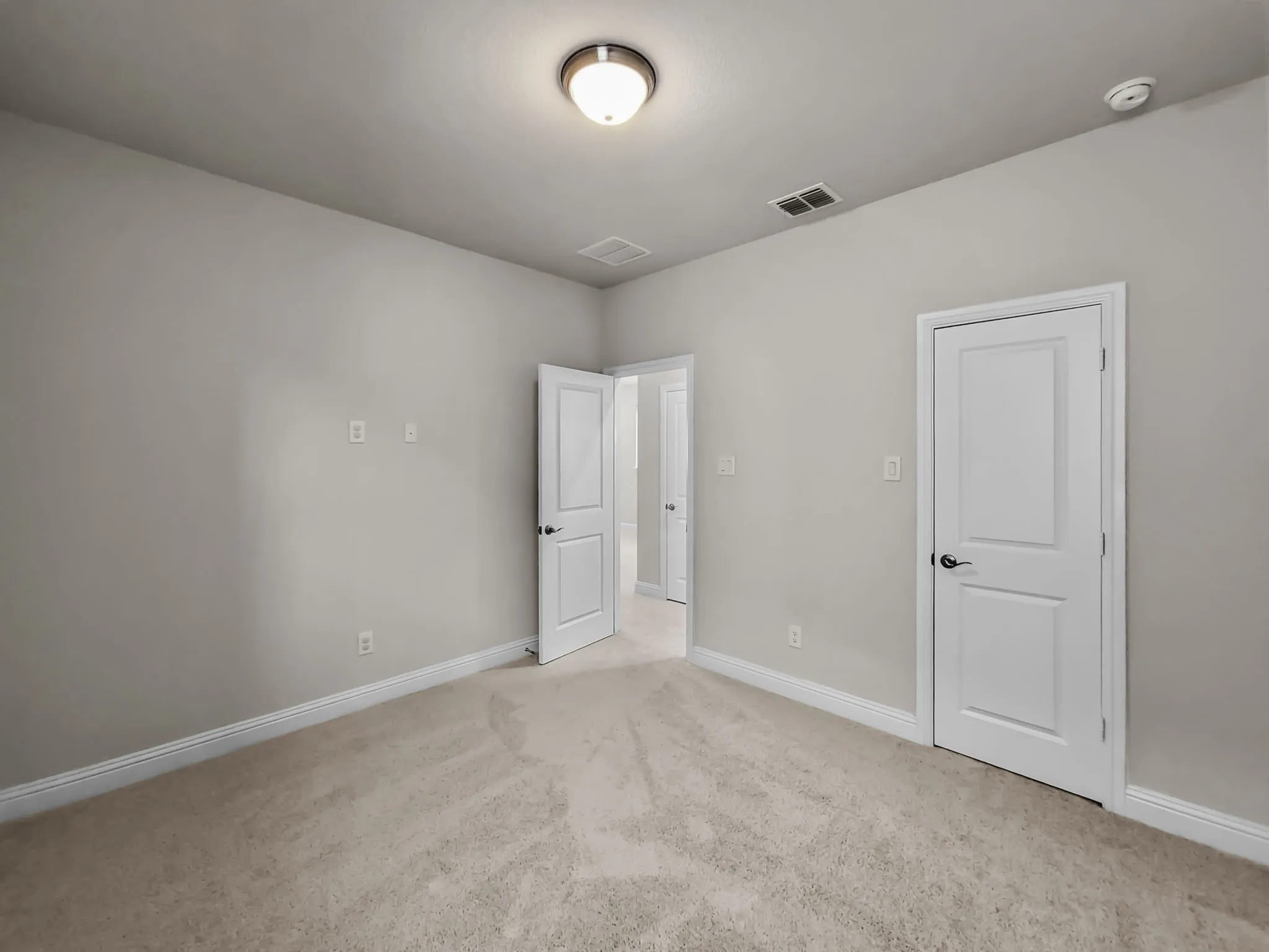 Neutral tone wall paint, light-colored carpeting, white trim, paneled interior doors, and a flush mount ceiling light fixture