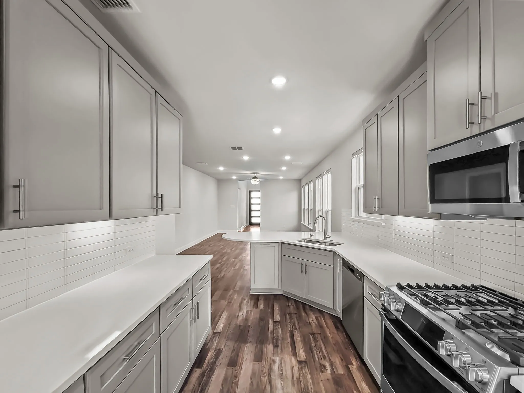 Kitchen featuring light gray cabinetry, white countertops, stainless steel appliances, white tile backsplash, and recessed lighting
