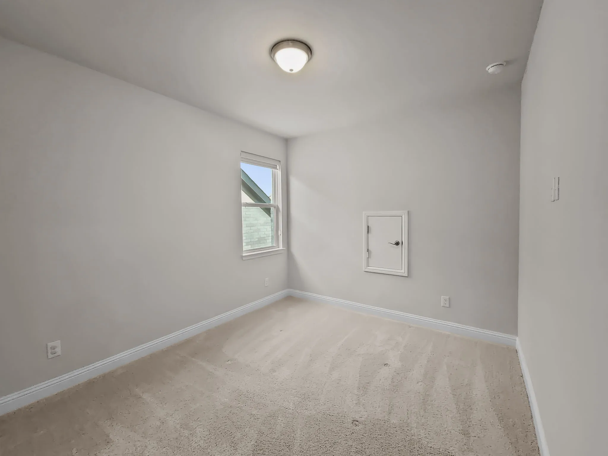 Carpeted room featuring a single window, a flush-mount ceiling light, and an access panel