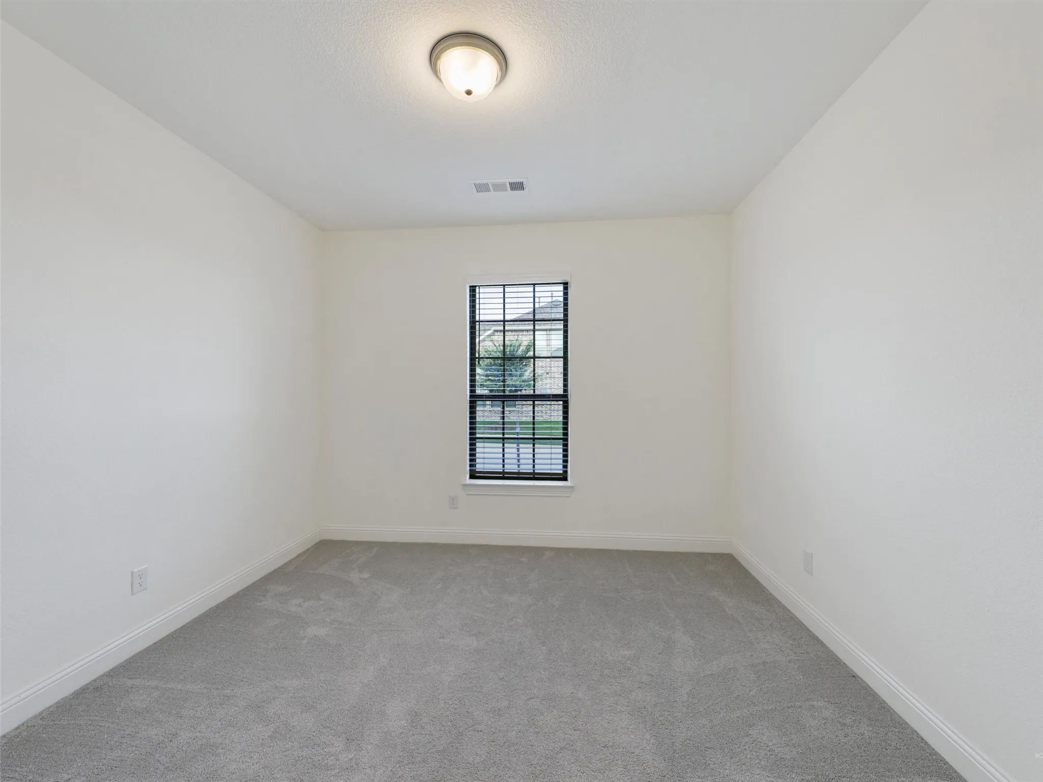 White painted walls, gray carpet, single window with blinds, flush mount ceiling light fixture, white trim