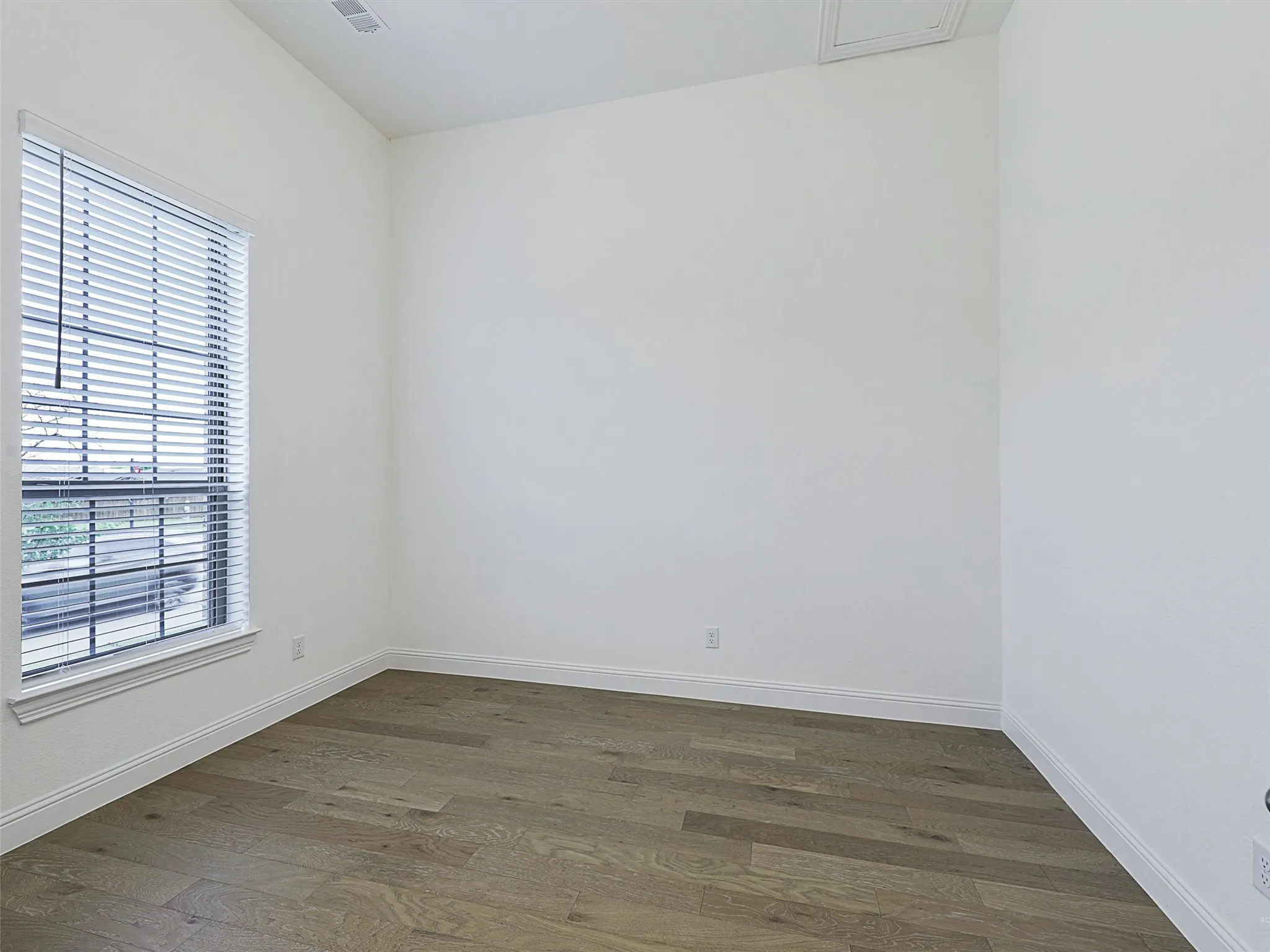 Wood-finish flooring, white walls, and a window with blinds