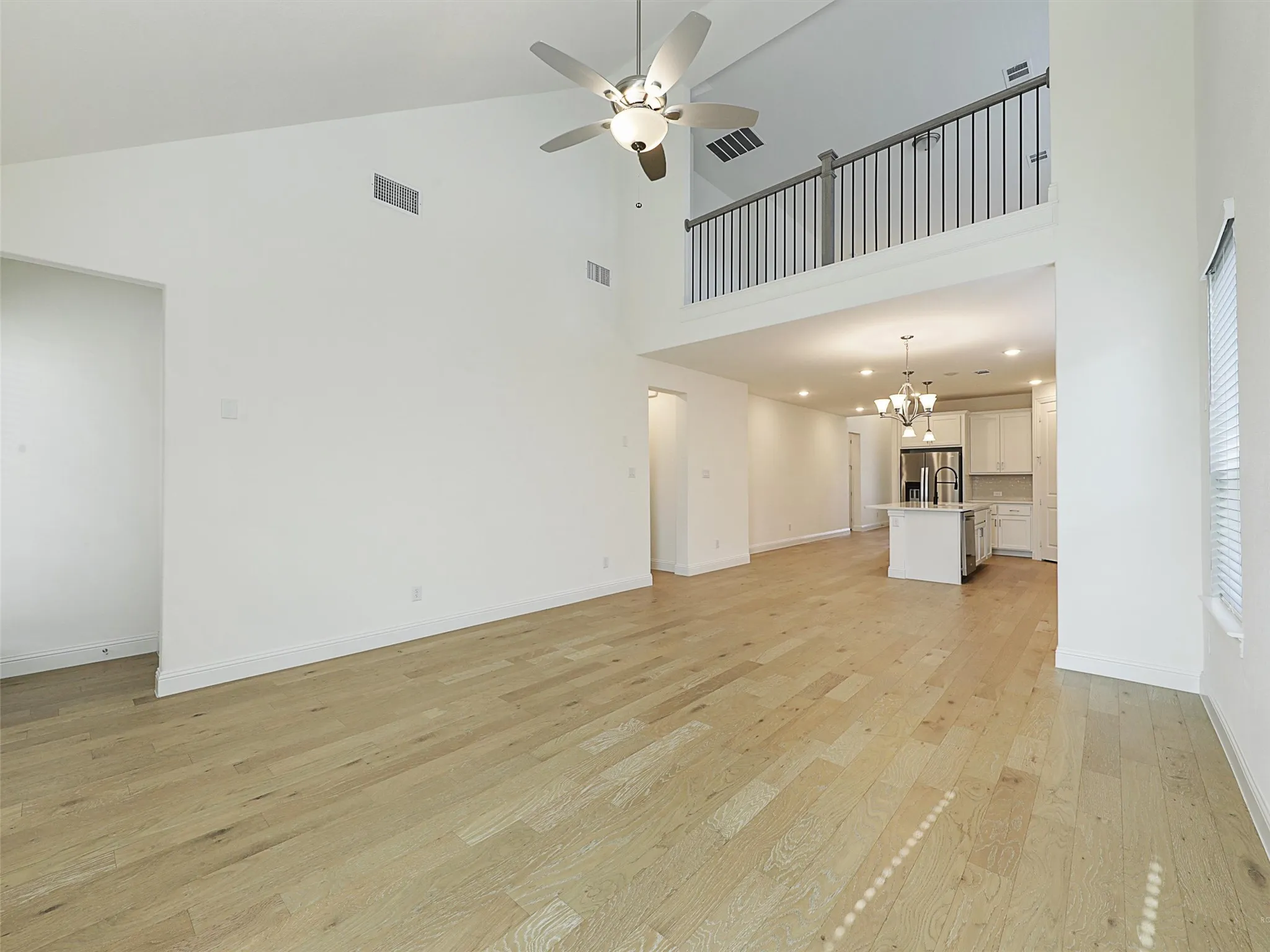 High ceilings with a ceiling fan, wood-finish flooring, and an open concept layout