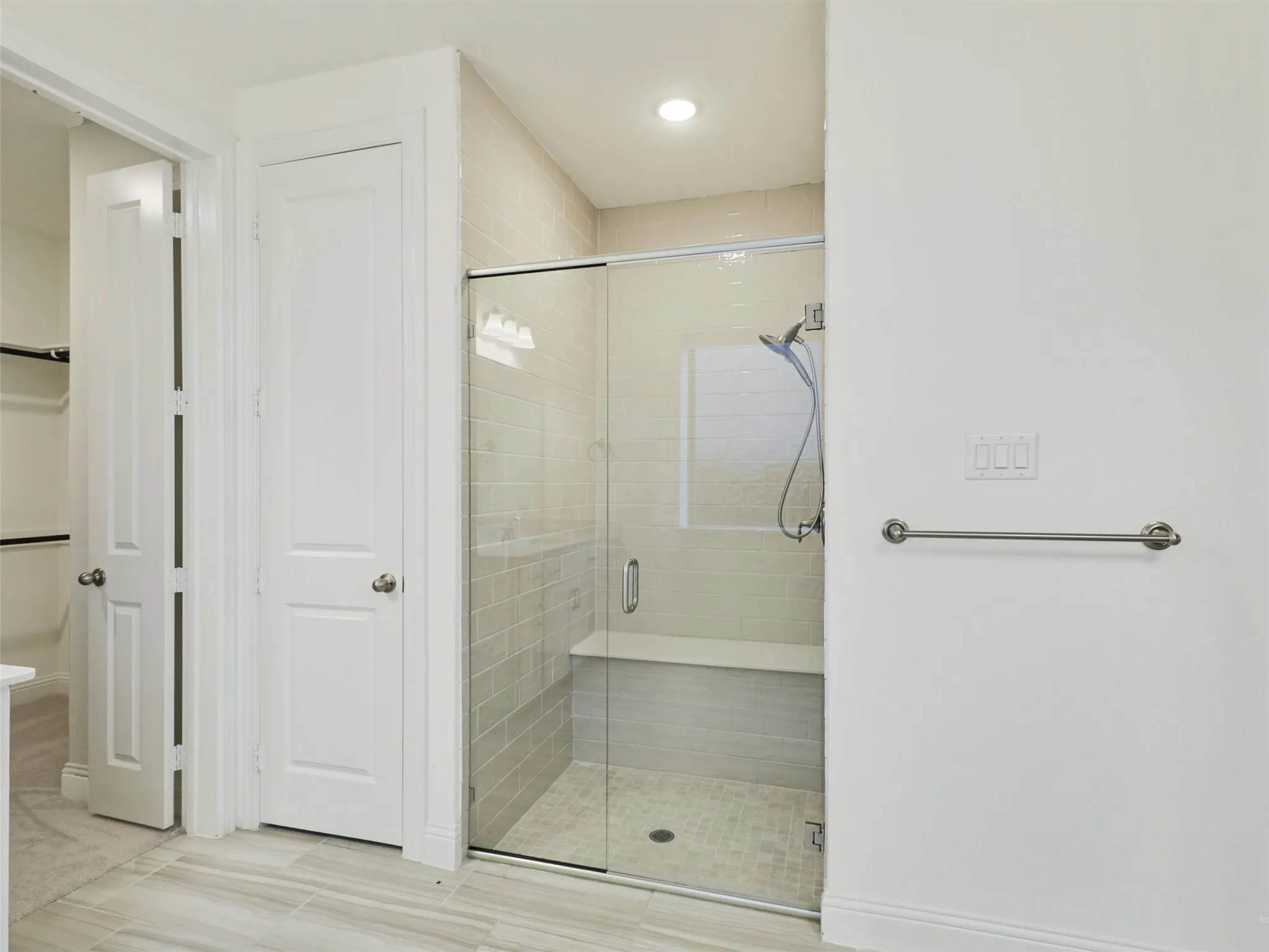 Glass-enclosed shower with a built-in bench, tiled shower walls, and a recessed window