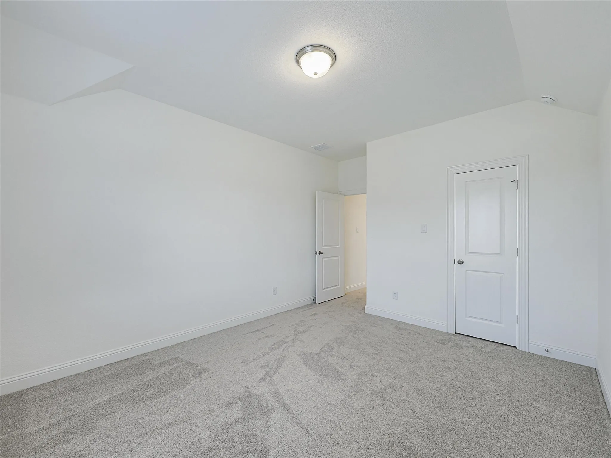 Spacious room with light gray carpet, white walls, and a semi-flush ceiling light fixture