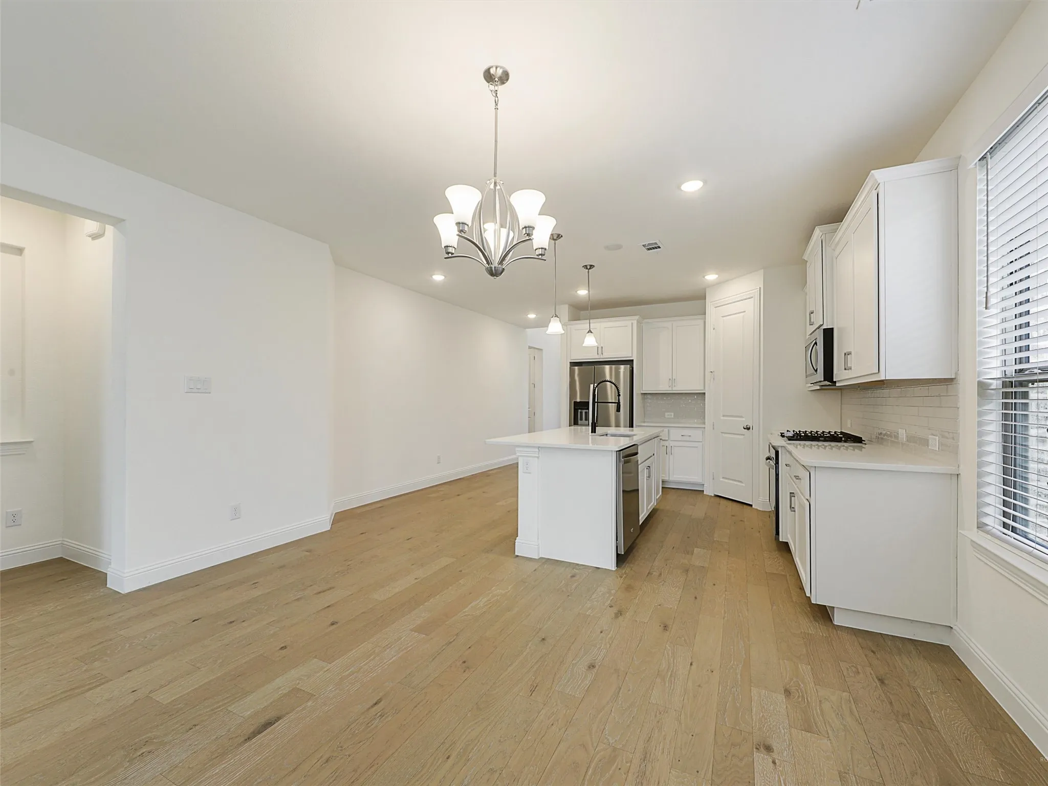 Open-concept living space featuring wood-finish flooring, recessed lighting, and a kitchen island with seating