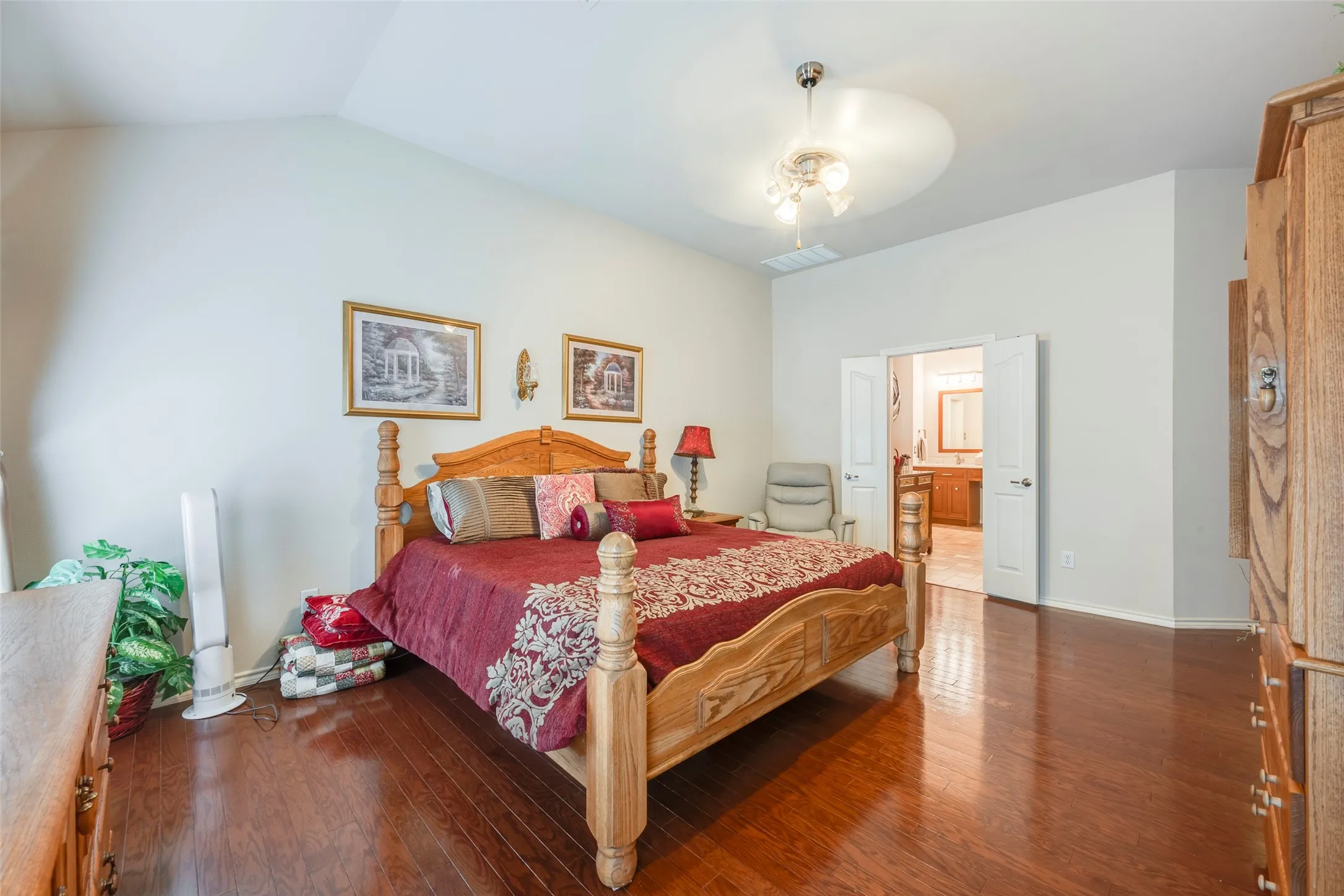 Vaulted ceiling, wood-finish flooring, ceiling fan with light fixture, double doors, and light-colored walls