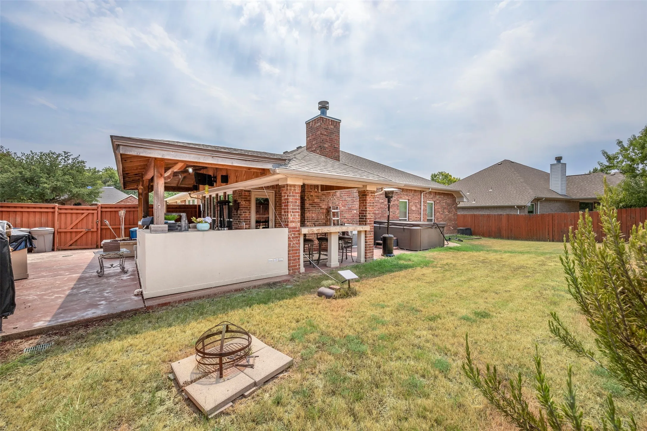 Spacious backyard featuring a covered patio, outdoor kitchen, and fire pit