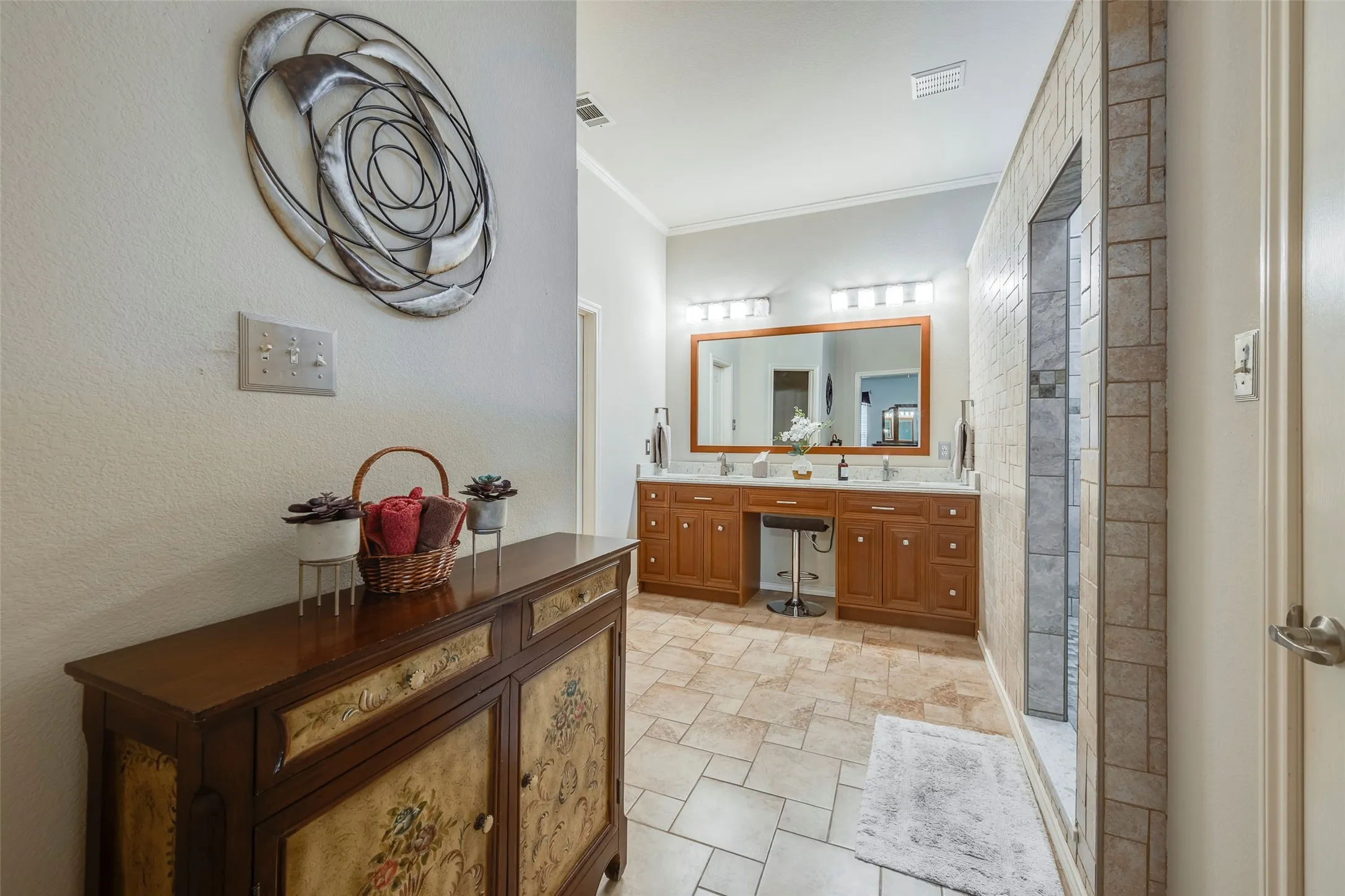 Dual vanity with integrated sinks, wood cabinetry, and a framed mirror with overhead lighting