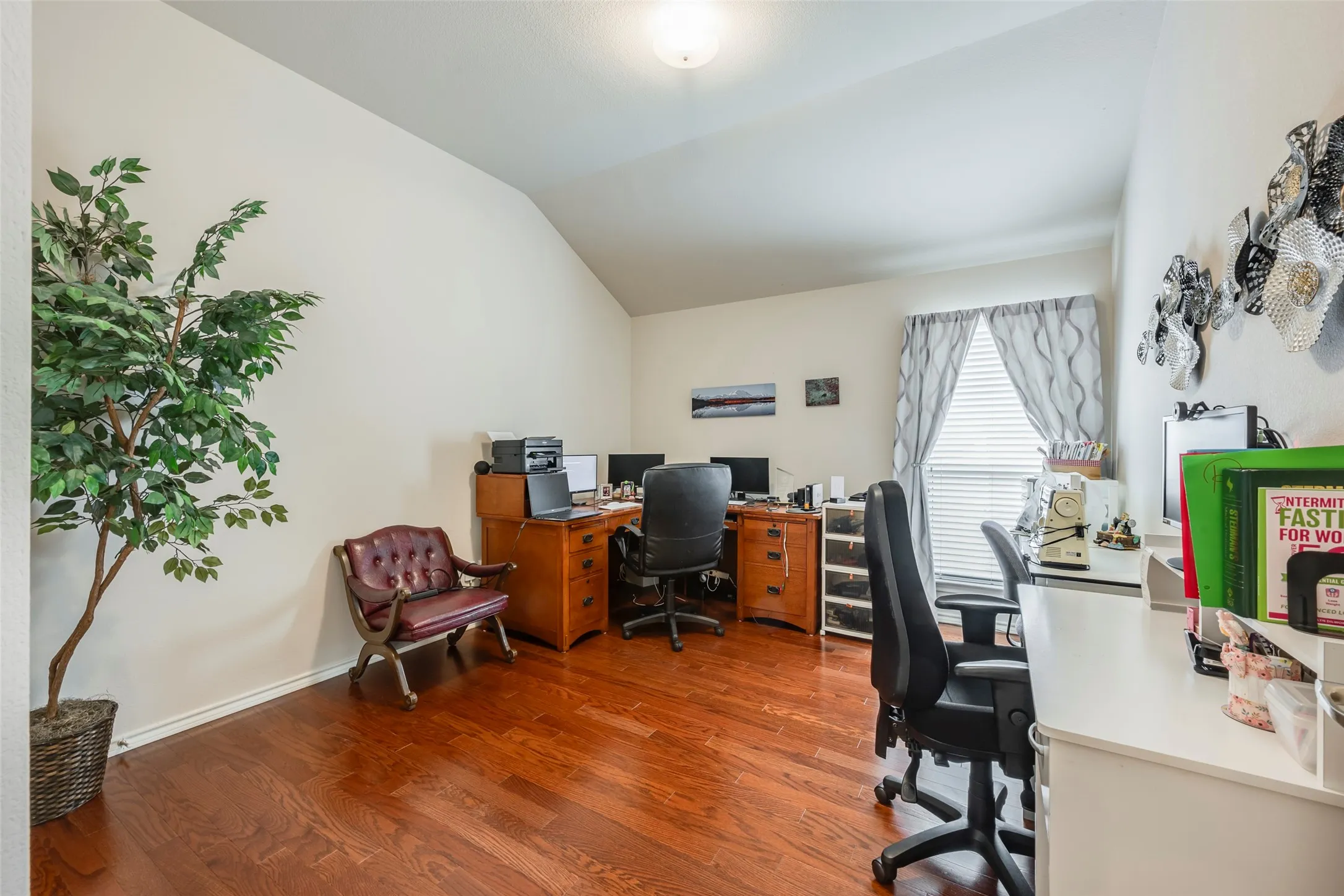 Vaulted ceiling, wood-finish flooring, and window with blinds