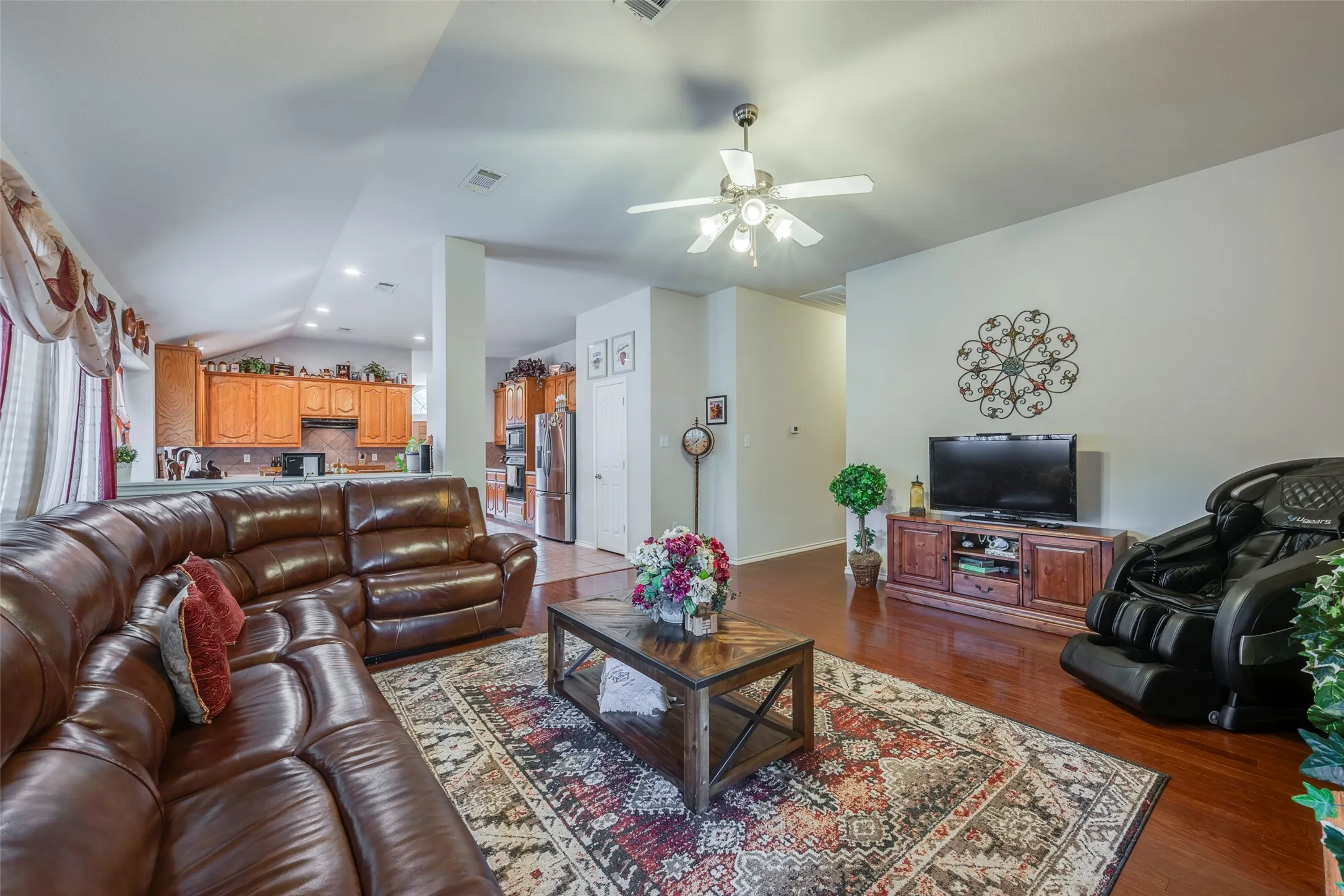Wood-finish flooring throughout, vaulted ceiling, recessed lighting, ceiling fan light fixture, and a kitchen featuring wood cabinetry