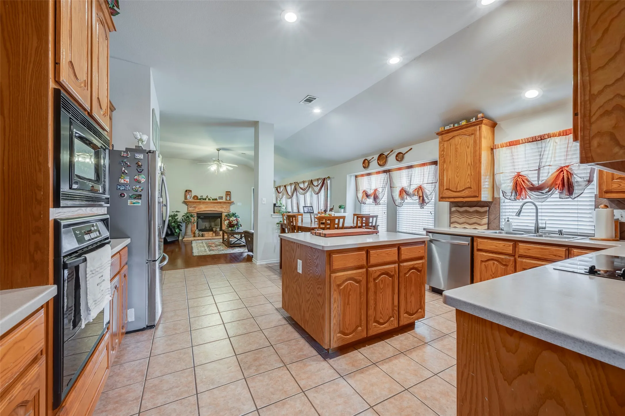 Kitchen featuring wood cabinetry, stainless steel appliances, a center island, and tile flooring