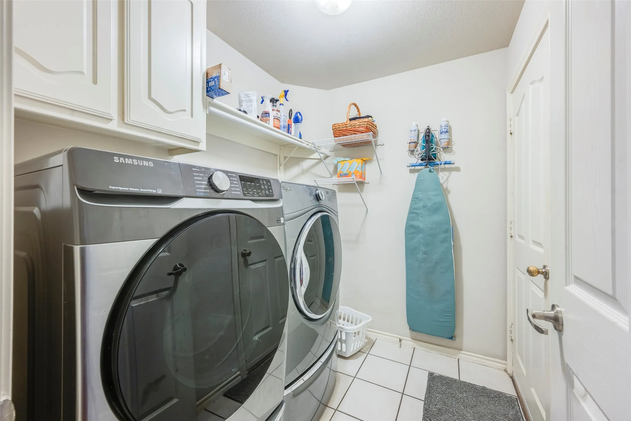 Built-in white cabinetry, wall-mounted shelving, and white tile flooring