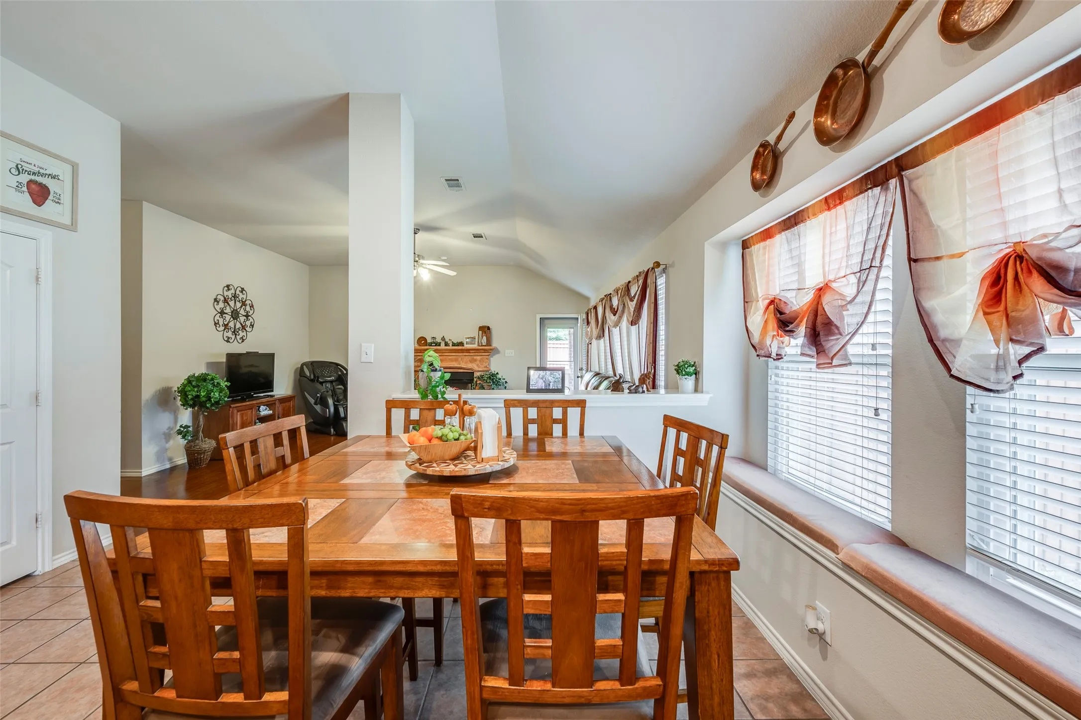 Dining area with tiled flooring, a window seat with a cushioned top, and a vaulted ceiling