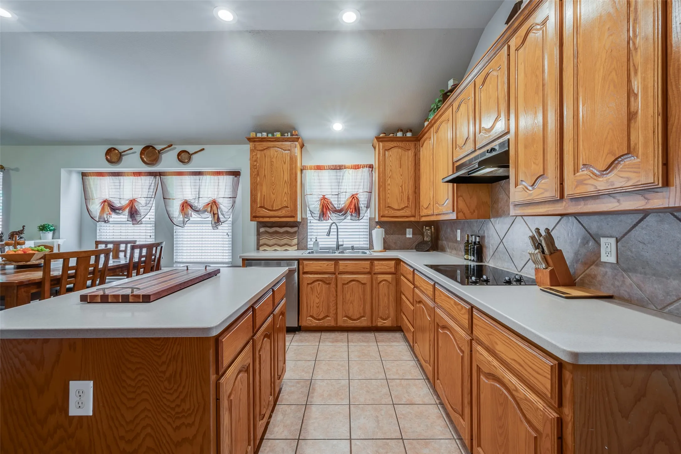 Kitchen featuring wood cabinetry, light countertops, tile flooring, a tile backsplash, and stainless steel appliances