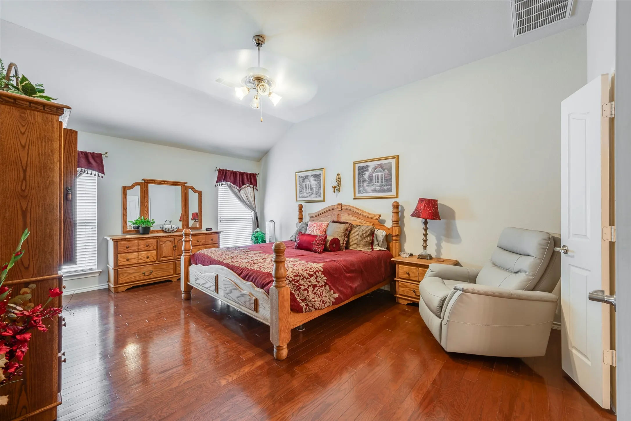 Vaulted ceiling with a ceiling fan, wood-finish flooring, two windows with blinds, and white interior doors