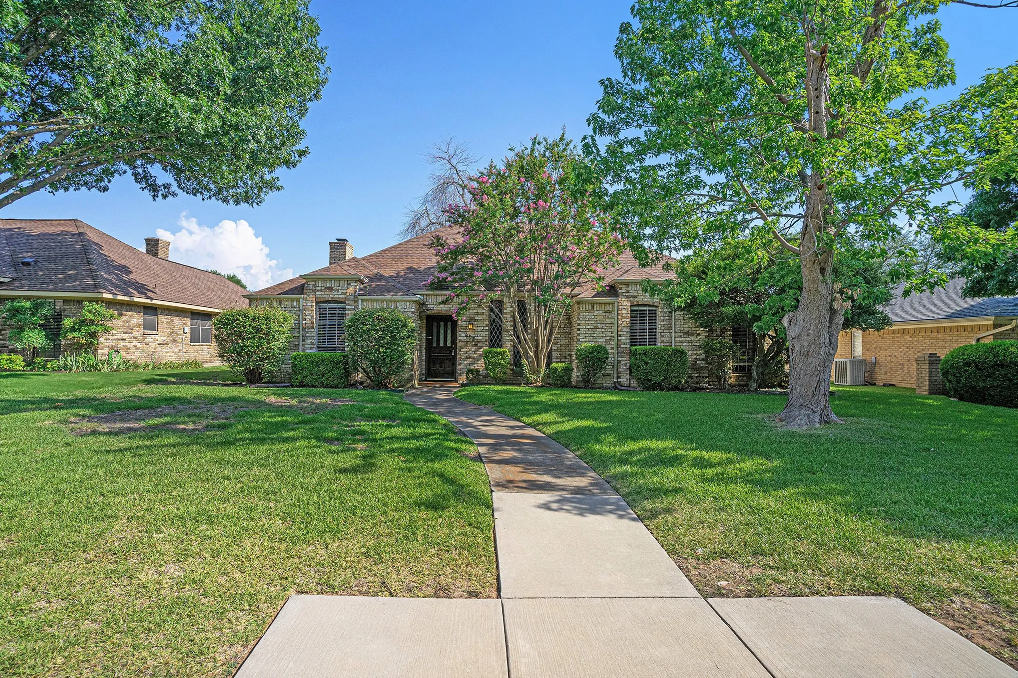 View of front of house with a front lawn, a chimney, and brick siding
