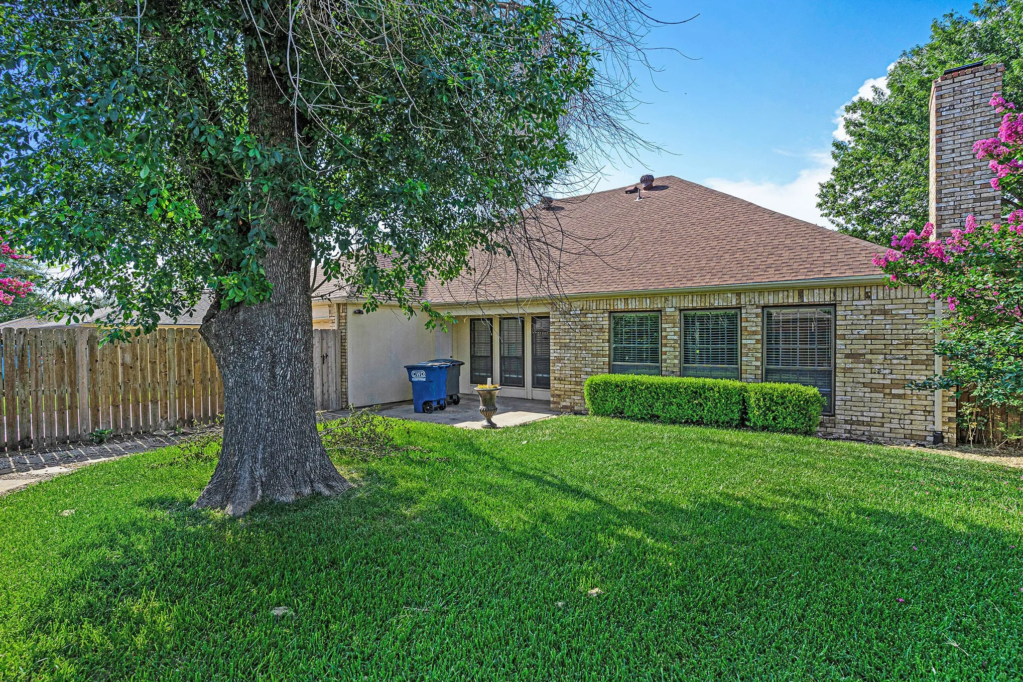 Back of property with roof with shingles, brick siding, and a patio