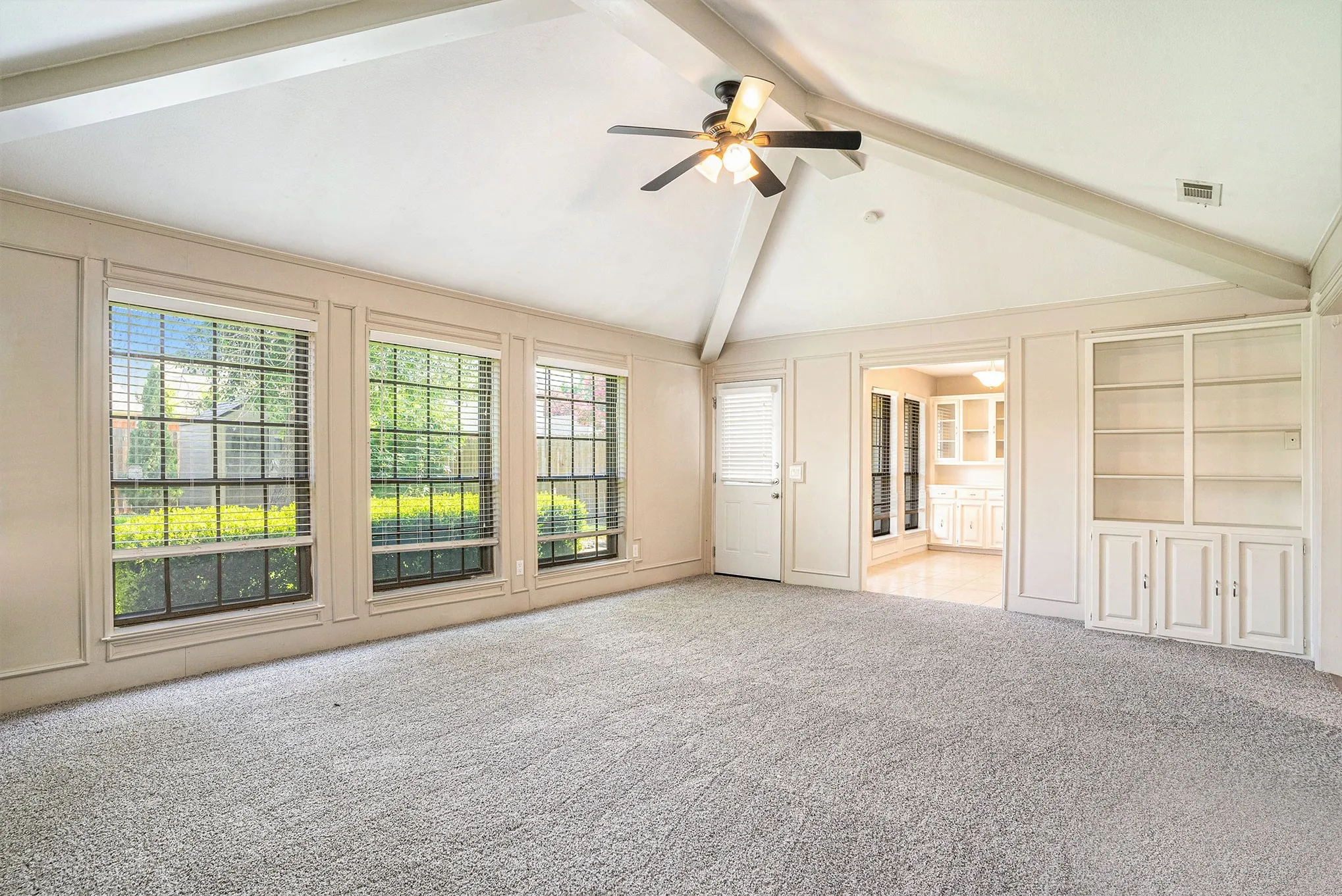 Unfurnished living room with beamed ceiling, high vaulted ceiling, carpet floors, a ceiling fan, and built in features
