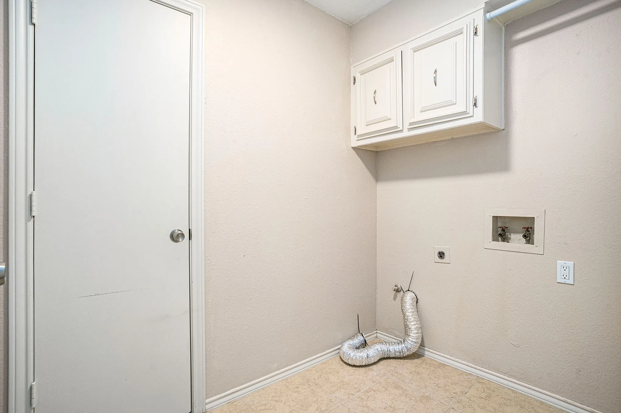 Laundry area featuring cabinet space, hookup for an electric dryer, tile patterned floors, and hookup for a washing machine