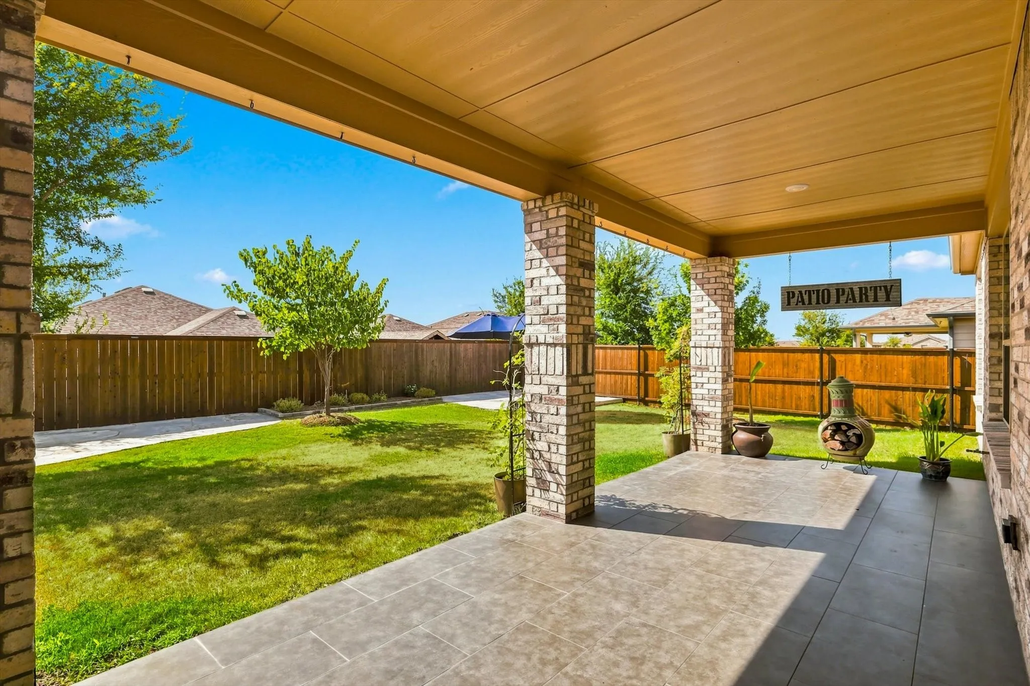Covered patio with tile flooring and brick columns