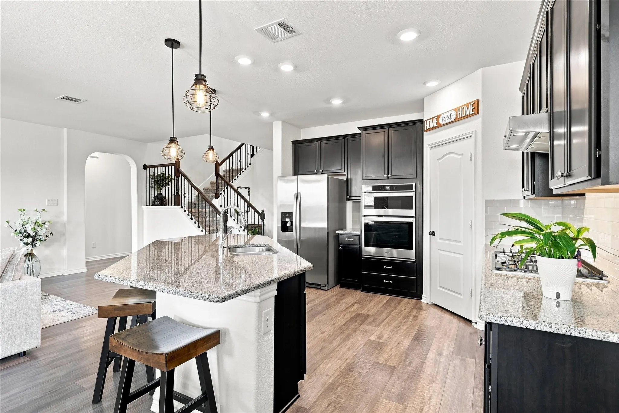 Kitchen featuring wood-finish flooring, granite countertops, and dark cabinetry