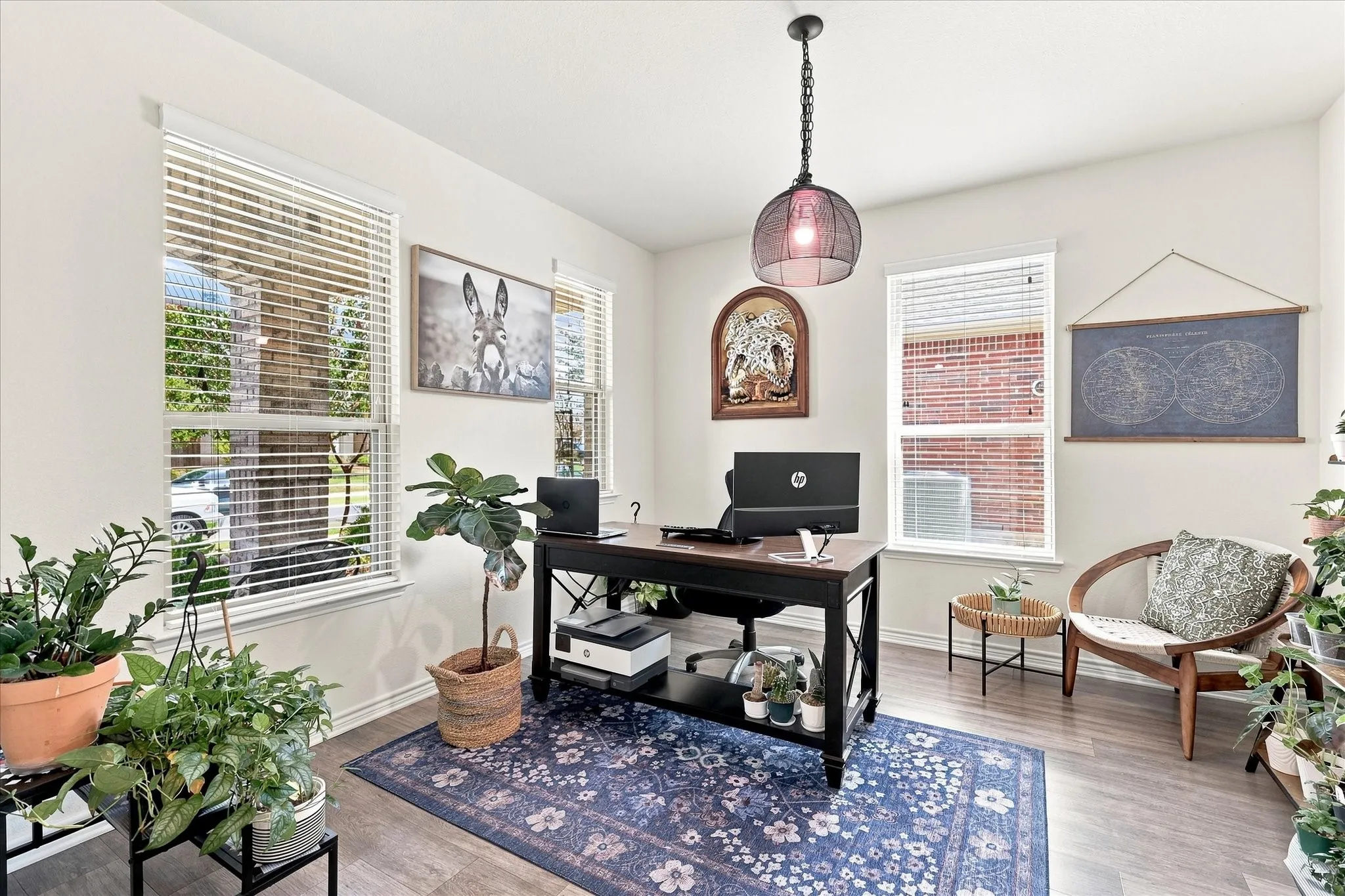 Neutral wall paint, multiple windows with blinds, wood-finish flooring, and a pendant light fixture