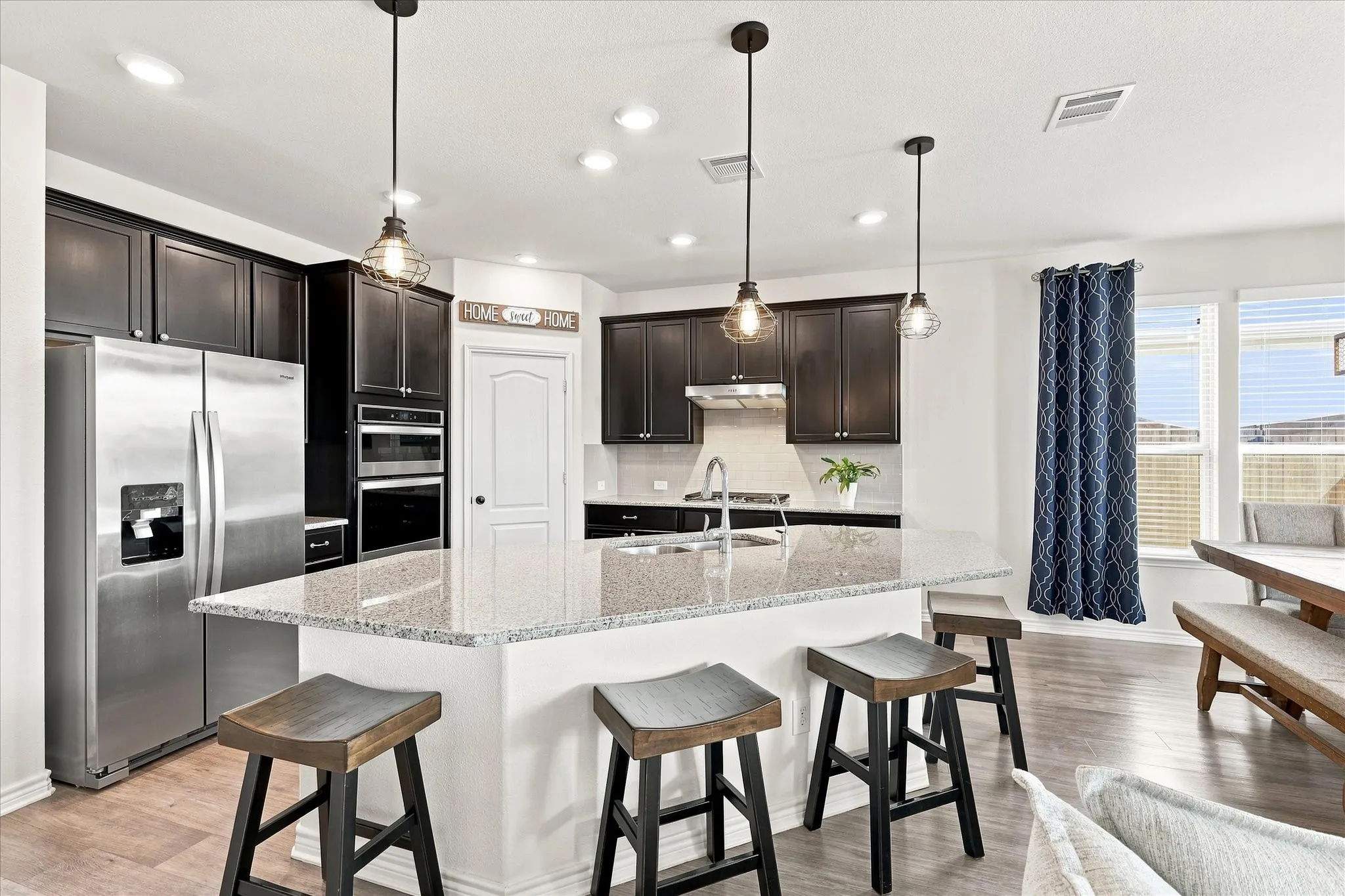 Kitchen featuring a large island with a stone countertop, recessed lighting, and dark wood-finish cabinetry