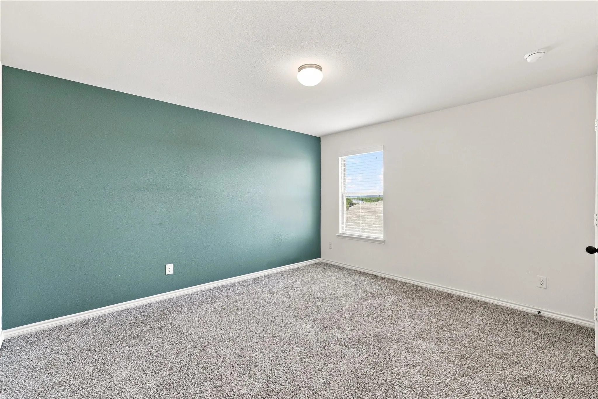 Plush carpet flooring, a single window with blinds, and recessed lighting