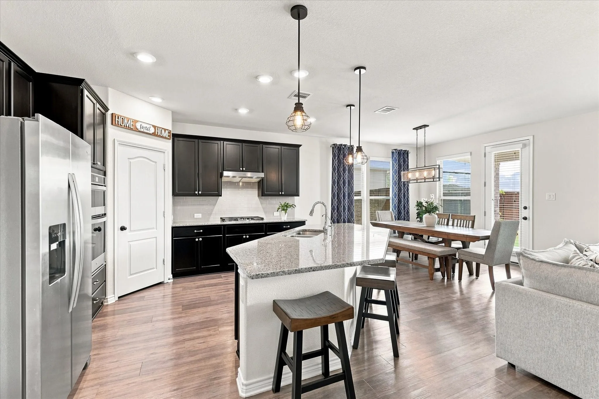Kitchen featuring wood-finish flooring, dark cabinetry, recessed lighting, stone countertops, and stainless steel appliances