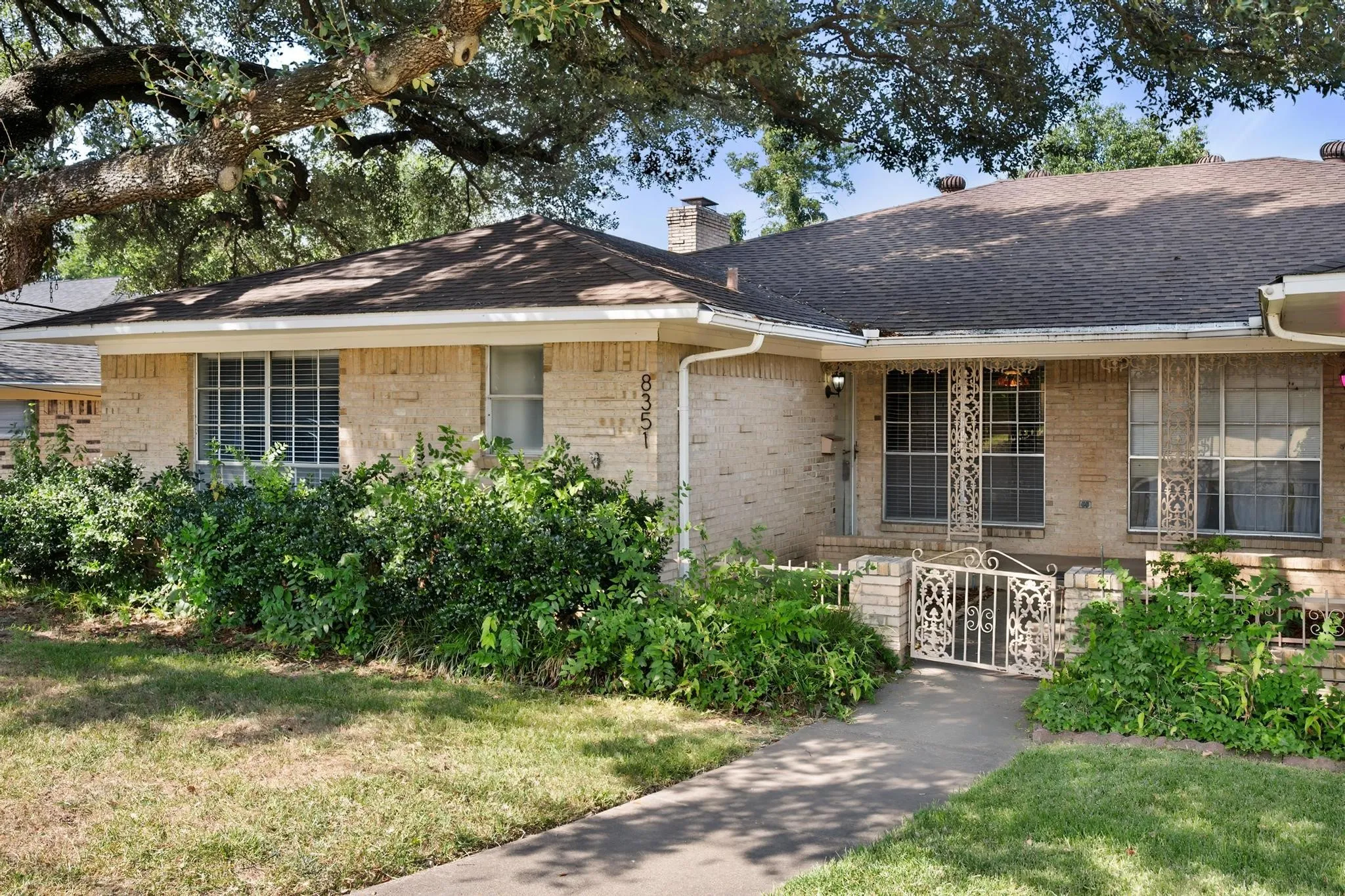 Brick exterior with a gabled roof and mature front landscaping