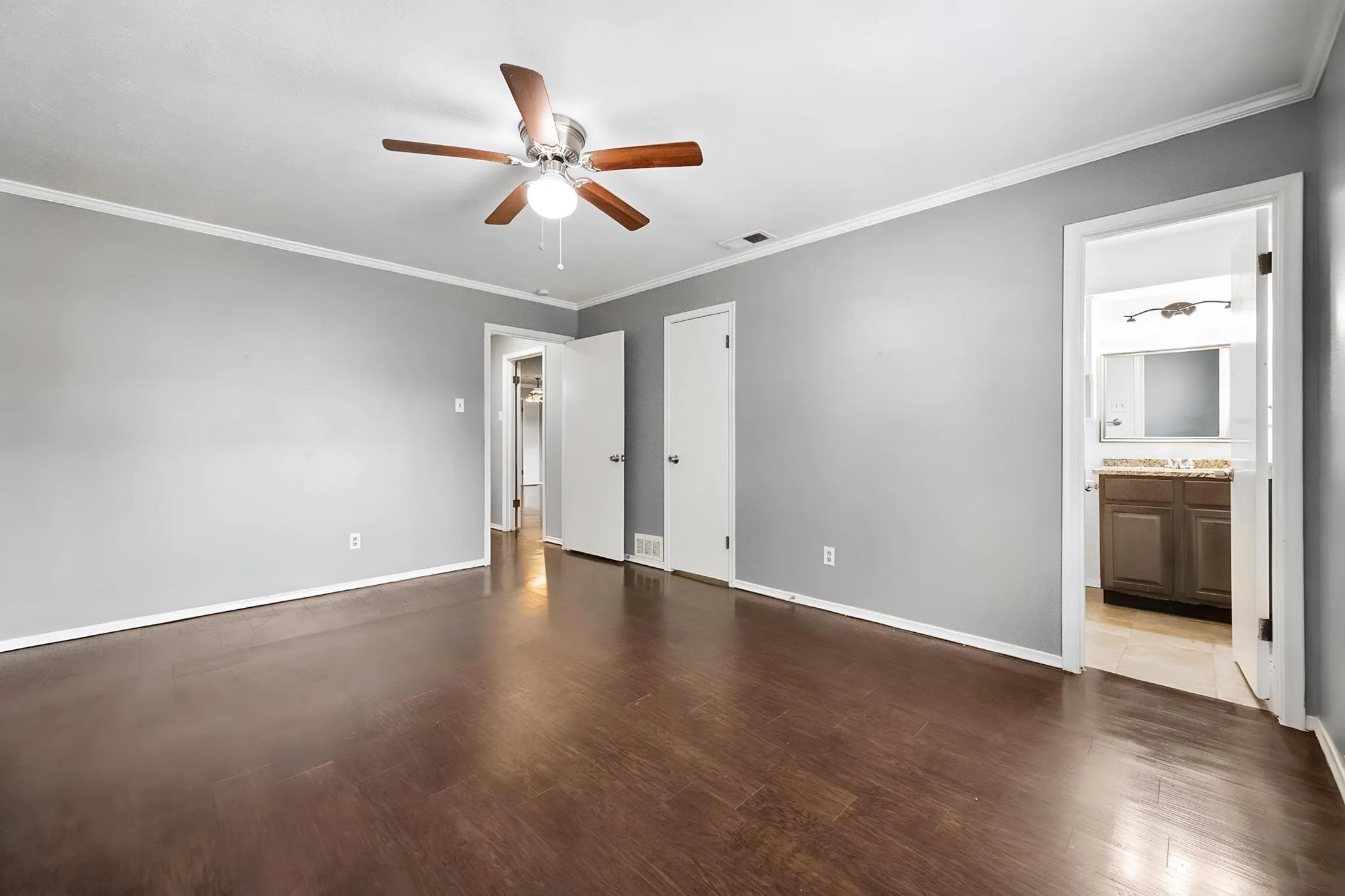 Wood-finish flooring, ceiling fan with integrated lighting, two panel doors, and neutral wall paint