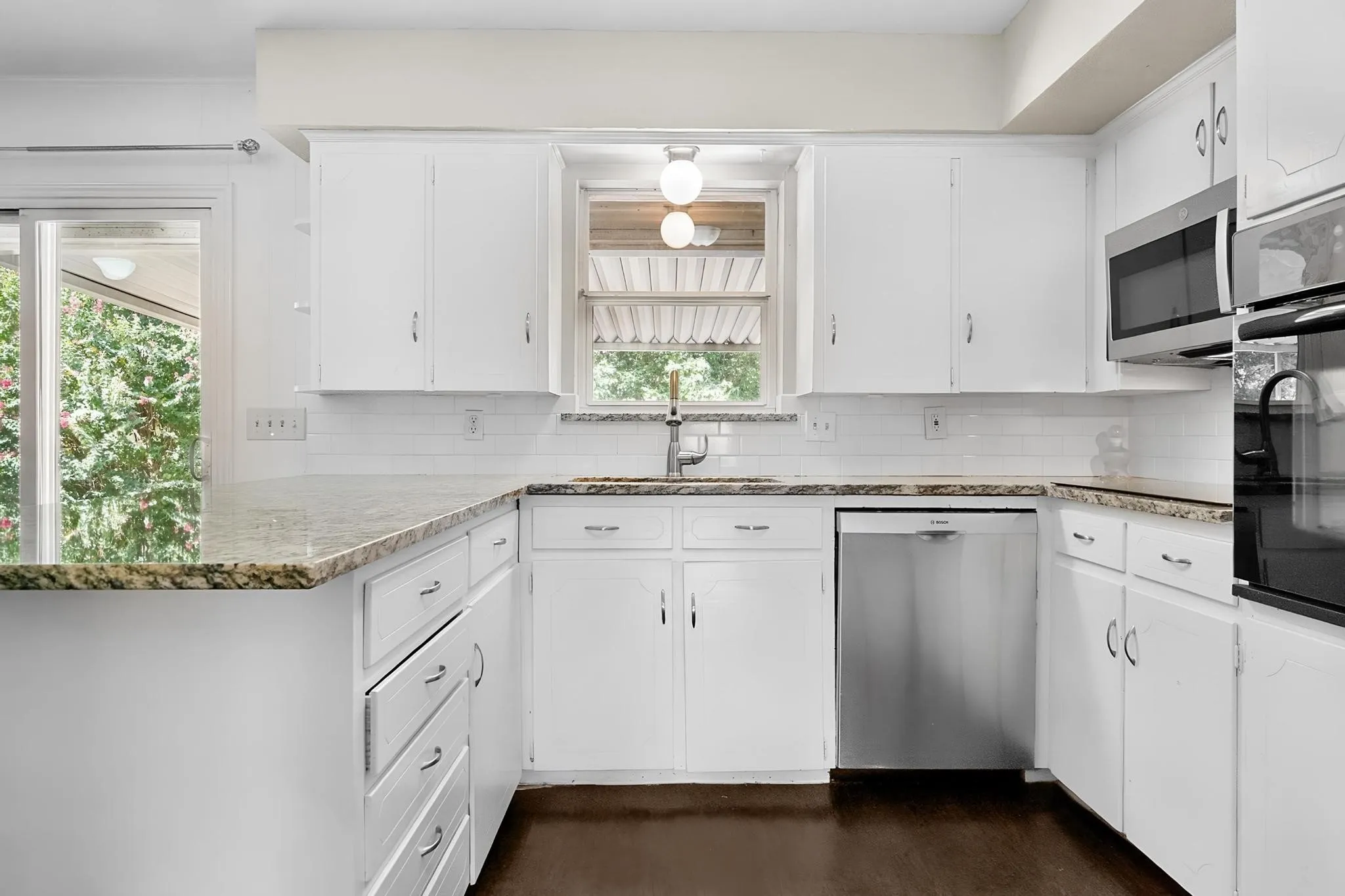 White cabinetry with silver hardware, granite-look countertops, stainless steel appliances, white subway tile backsplash, and dark wood-finish flooring