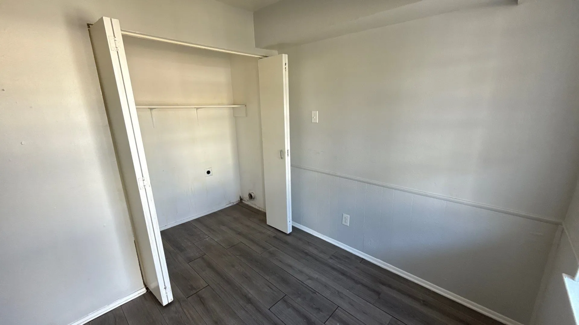 Wood-finish flooring, built-in closet, and light gray walls