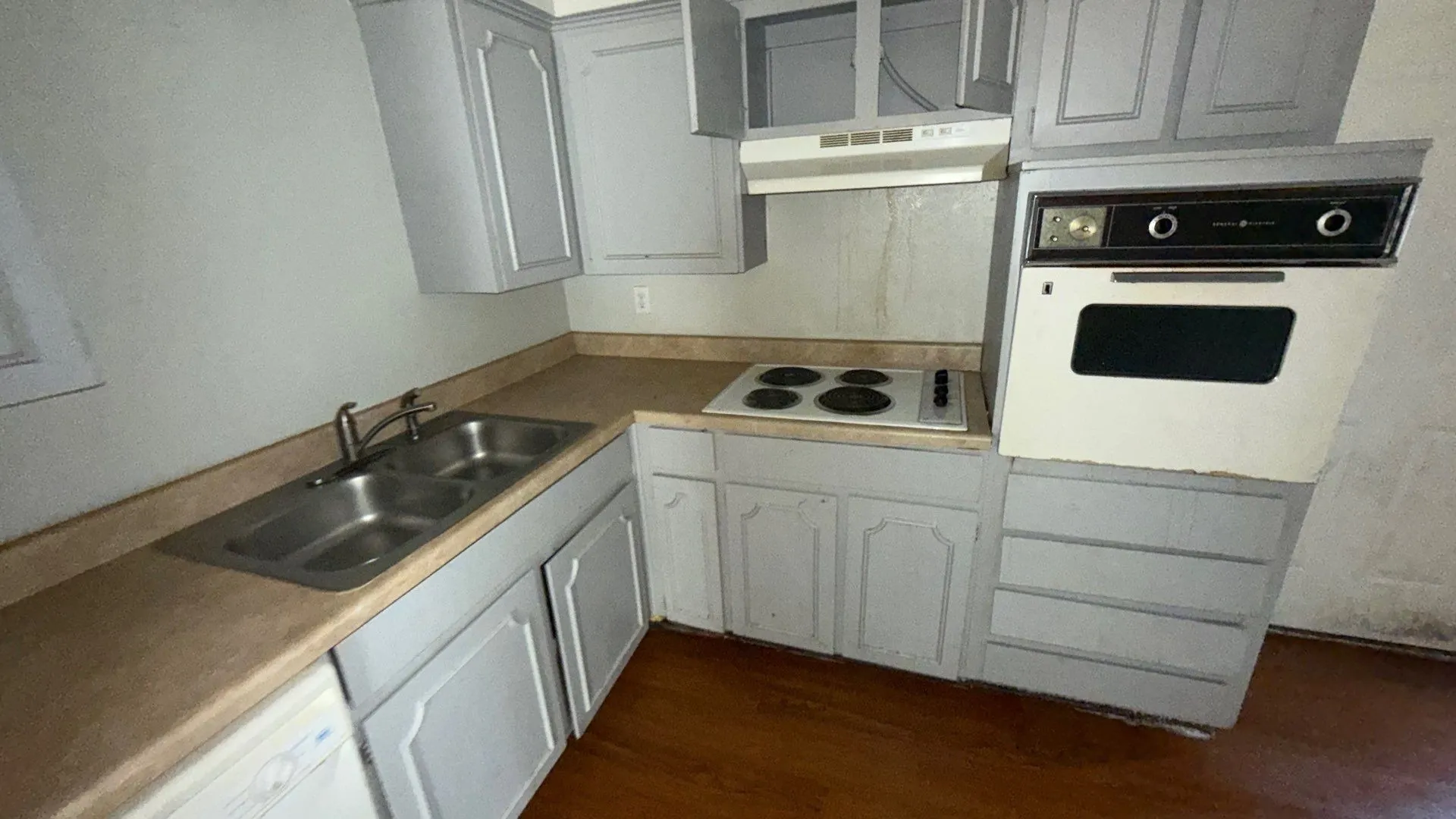Kitchen featuring a double basin stainless steel sink, built-in cooktop, wall oven, and wood-finish flooring