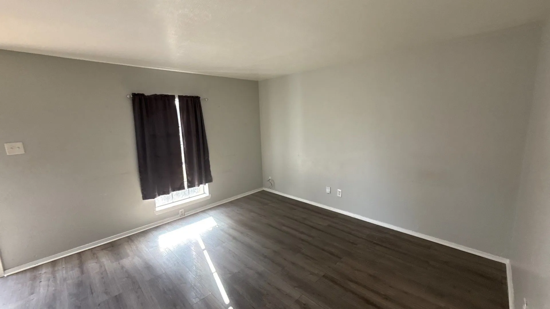 Wood-finish flooring, light gray wall paint, and a window with white trim