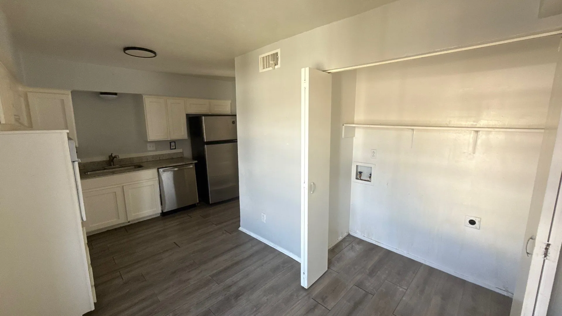 Kitchen featuring white cabinetry, stainless steel dishwasher, and wood-finish flooring