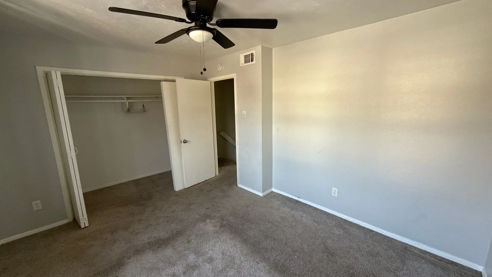 Carpeted bedroom featuring a ceiling fan with integrated lighting, a built-in closet with bi-fold doors, and neutral wall paint