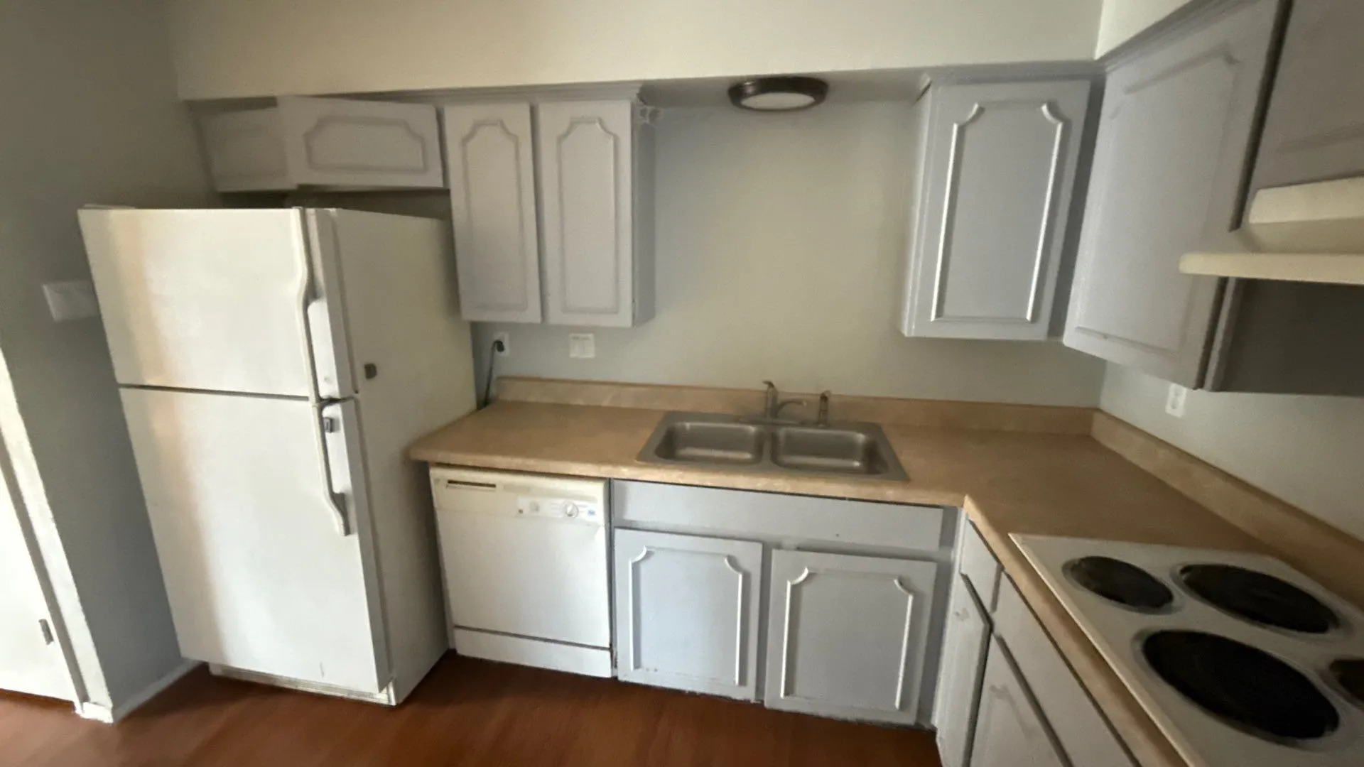 Kitchen featuring wood-finish flooring, painted cabinetry, a dual basin sink, and a white electric range