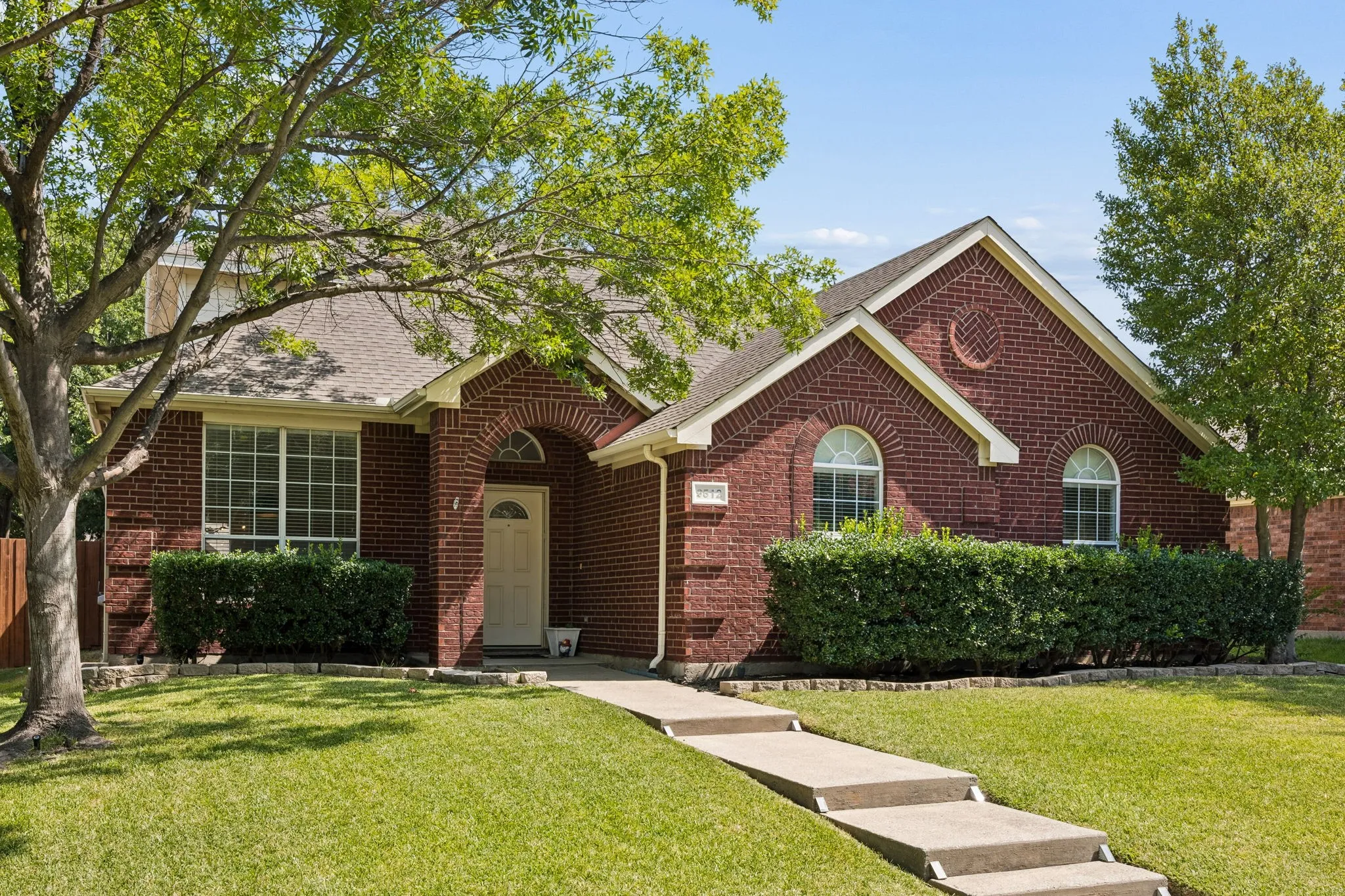 Brick exterior with arched entryway, architectural windows, and a stepped concrete walkway
