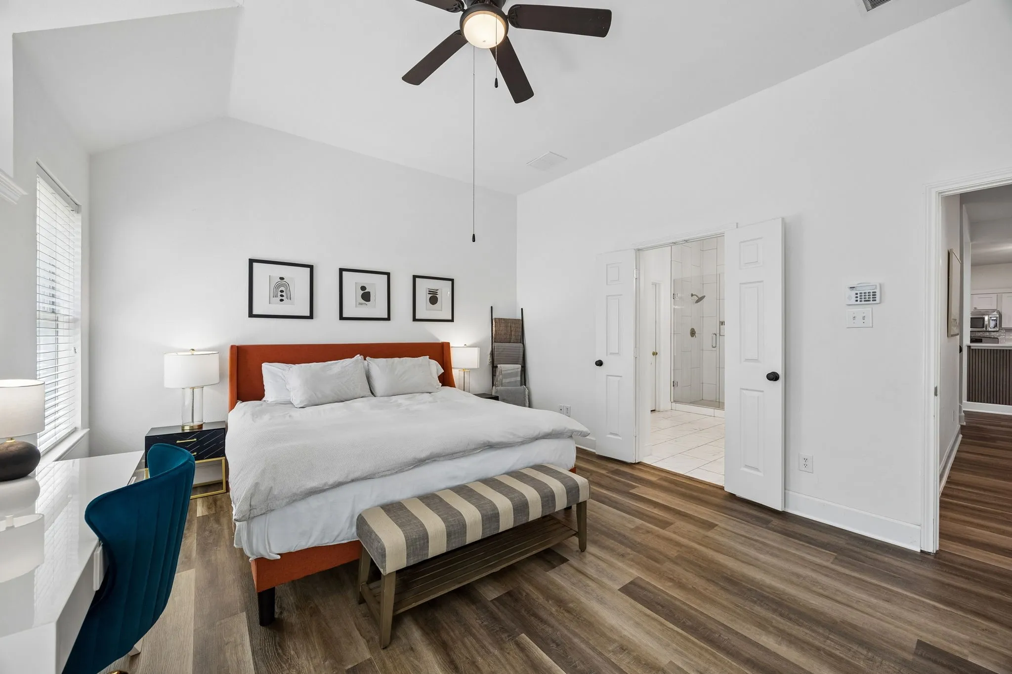 Vaulted ceiling, wood-finish flooring, ceiling fan, window with blinds, white paneled double doors