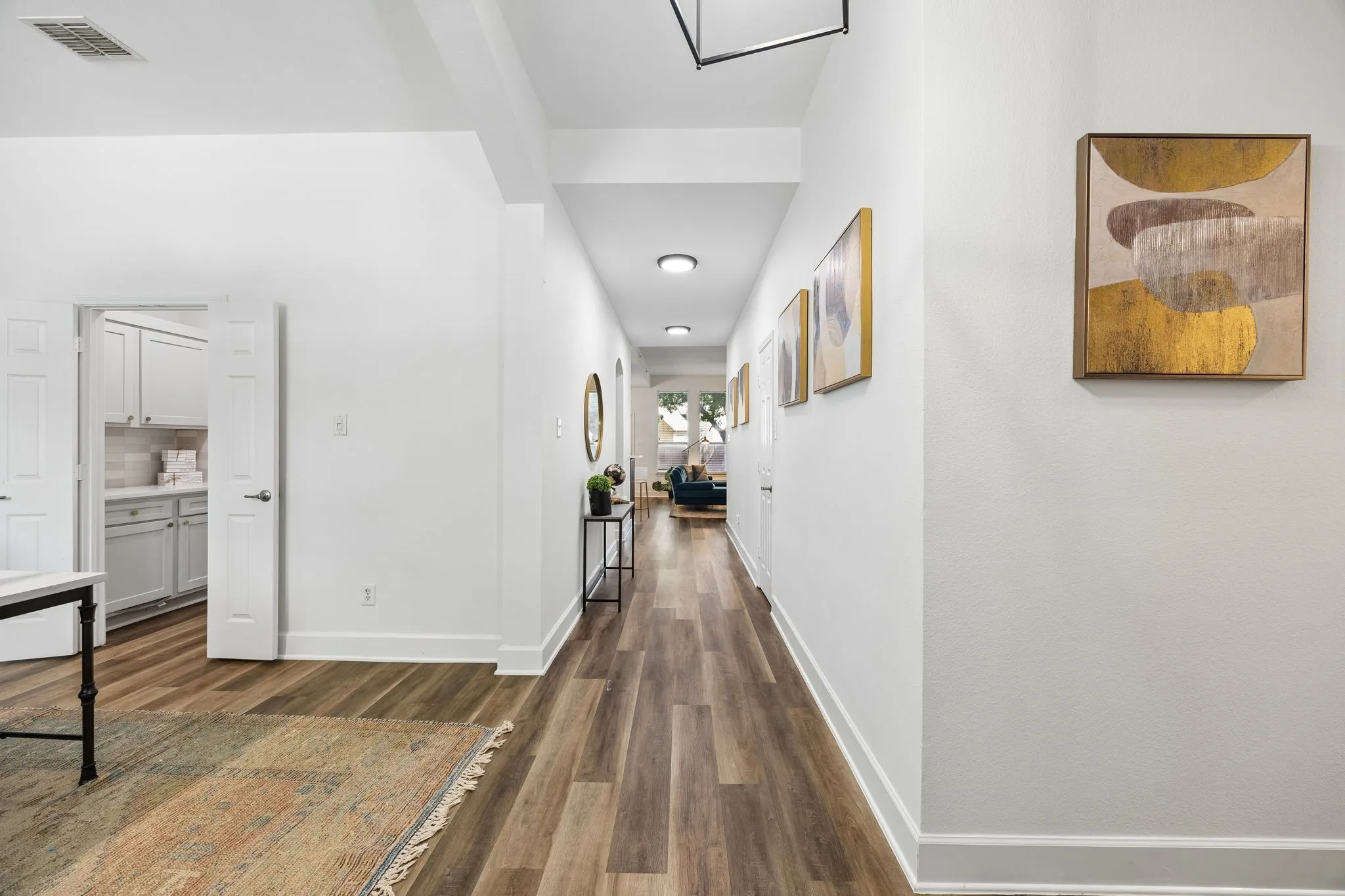 Elongated hallway with wood-finish flooring, recessed lighting, and white walls